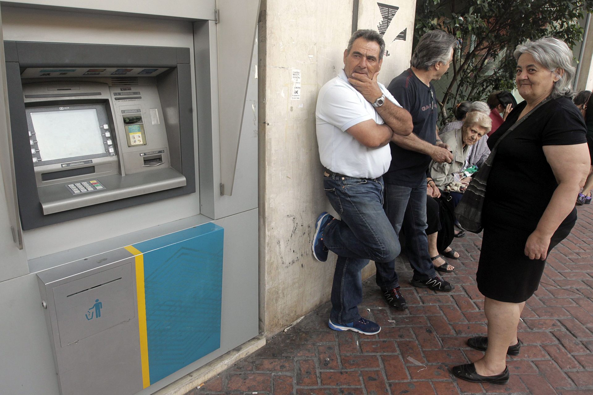 epa04823261 People wait in line outside a National Bank of Greece branch, in Athens, Greece, 29 June 2015. Greece is imposing capital controls and ordering the closure of banks, Prime Minister Alexis Tsipras said 28 June, as Athens scrambled to avert the collapse of the country's financial system.  EPA/ORESTIS PANAGIOTOU