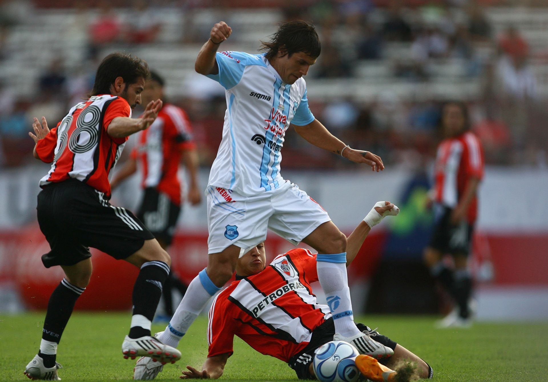 BUENOS AIRES, ARGENTINA - FEBRUARY 10:  Marcelo Quinteros of Gimnasia de Jujuy is tackled by Alexis Sanchez of River Plate with Matias Abelairas of River Plate watching on during the Primera Division closing season match between River Plate and Gimnasia de Jujuy at the Estadio Monumental on February 10, 2008 in Buenos Aires, Argentina.  (Photo by Julian Finney/Getty Images)