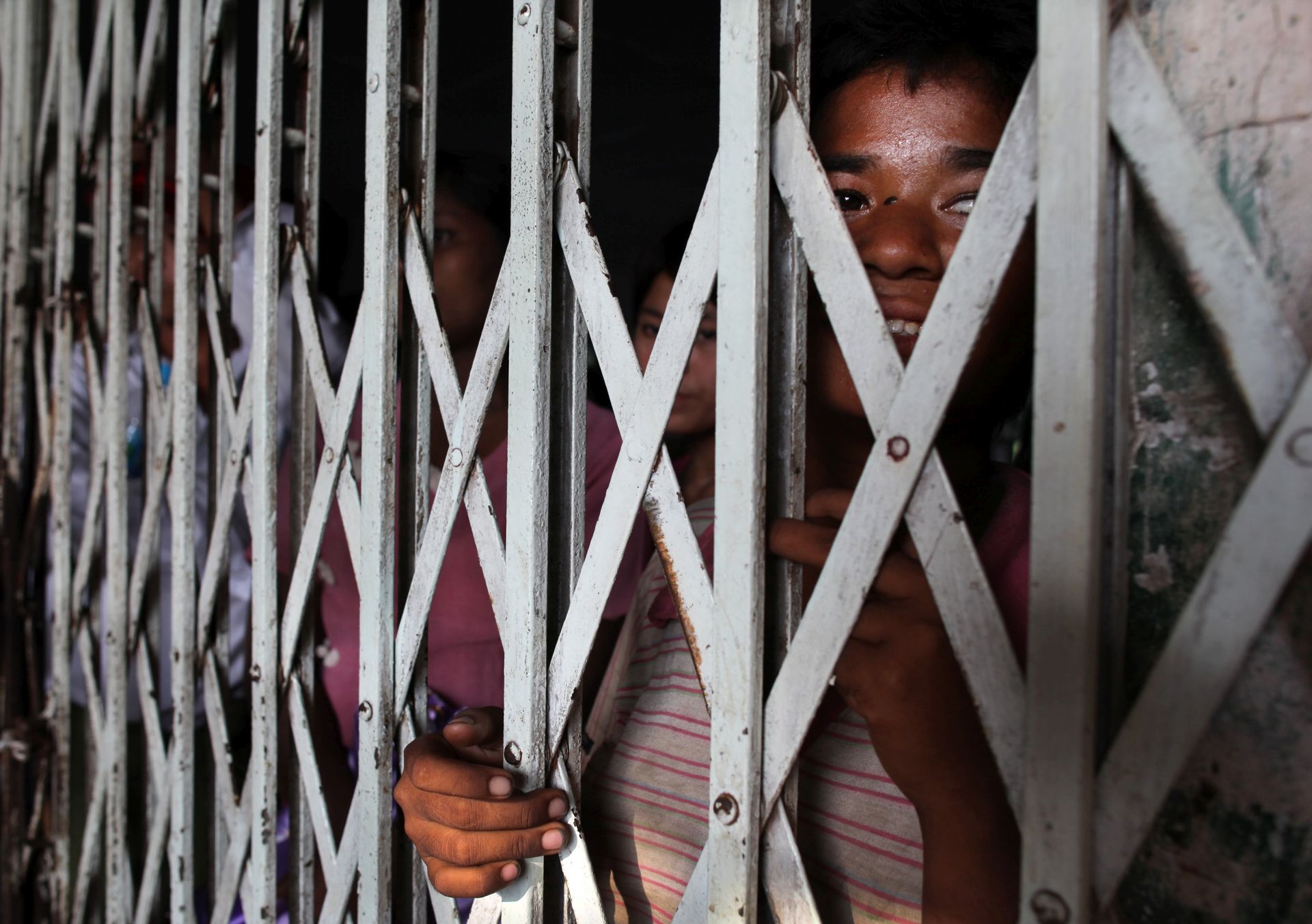 YANGON, MYANMAR - MAY 2:  A Burmese woman peeks her face through a fence waiting for the ferry gates to open so passengers can board on May 2, 2009 in the downtown area of Yangon, Myanmar (Burma). Currently the U.S government has been urged by two major Burmese opposition groups to maintain and stiffen its economic sanctions against the military junta until all political prisoners are released. At a recent briefing U.S secretary of State Hillary Clinton stated that she remained very concerned about the current situation in Burma. The Burmese government spends only 0.3% of the gross domestic product on health, the lowest amount worldwide, according to the United Nations Development Program 2008 survey (UNDP). Many low income people living in the poverty-stricken rural areas can't even afford to have a meal in a day.  In Burma the poorest suffer the most since they can't afford to pay for healthcare.  (Photo Paula Bronstein/Getty Images)