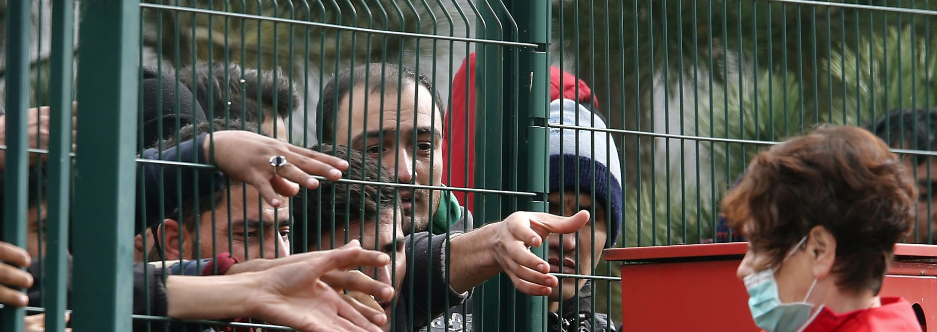 epa04986604 A Slovenian Red Cross activist feeds migrants behind a fence at the Refugee camp in Brezice, Slovenia, 21 October 2015. More and more migrants arrive in Slovenia on alternative routes to enter the European Union. Diplomatic tensions have flared amid migrant bottlenecks at the Slovenian, Croatian and Serbian borders that have left hundreds of people out in the mud, rain and cold. Ten leaders from the European Union and Balkan countries will meet in Brussels on 25 October to hold talks on the 'unfolding emergency' involving migrants in the western Balkans.  EPA/ANTONIO BAT