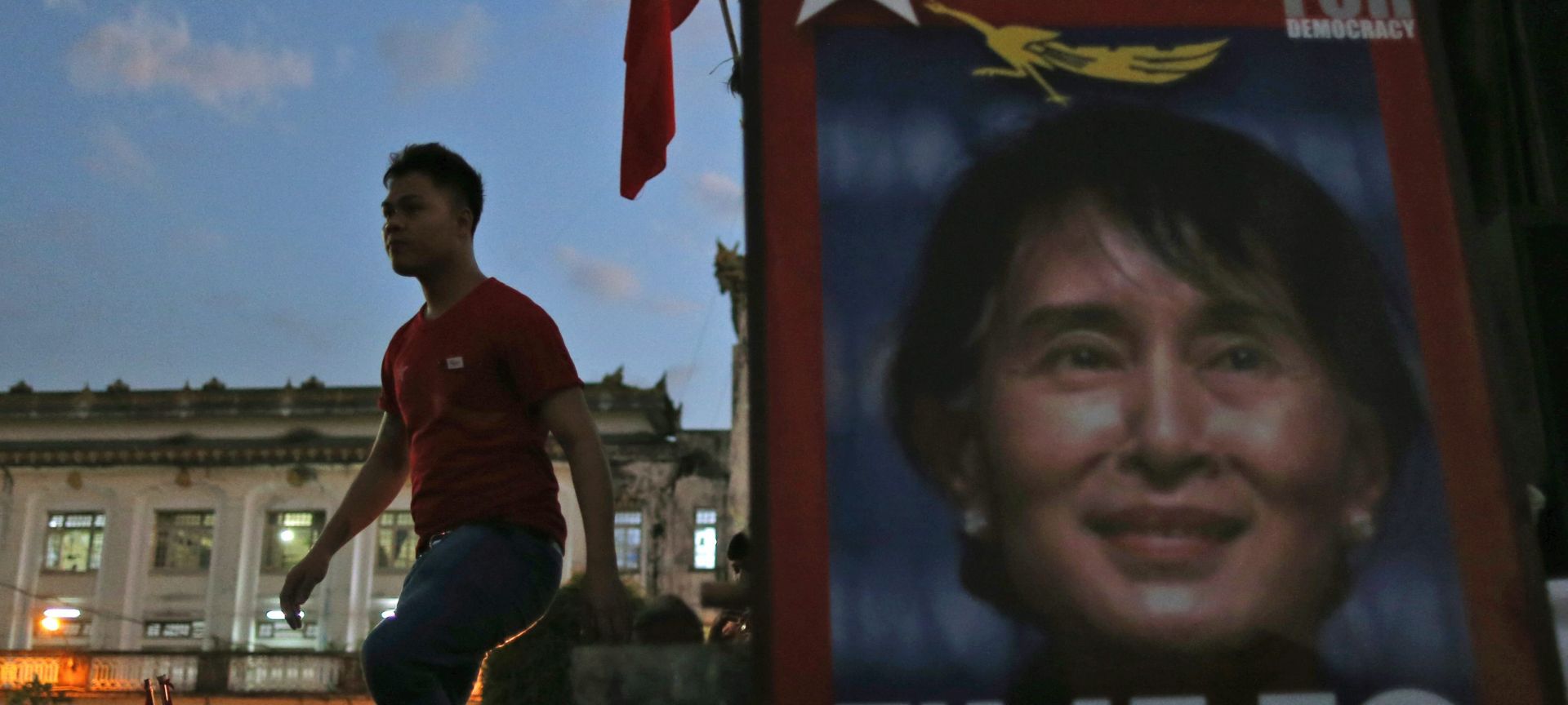 epa05012308 A supporter walks next to a poster of the National League for Democracy (NLD) party's leader Aung San Suu Kyi during their election campaign rally outside the Central Railway Station in Yangon, Myanmar, 05 November 2015. Myanmar will hold the general elections on 08 November 2015 which will be the first genuinely contested poll for 25 years.  EPA/RUNGROJ YONGRIT