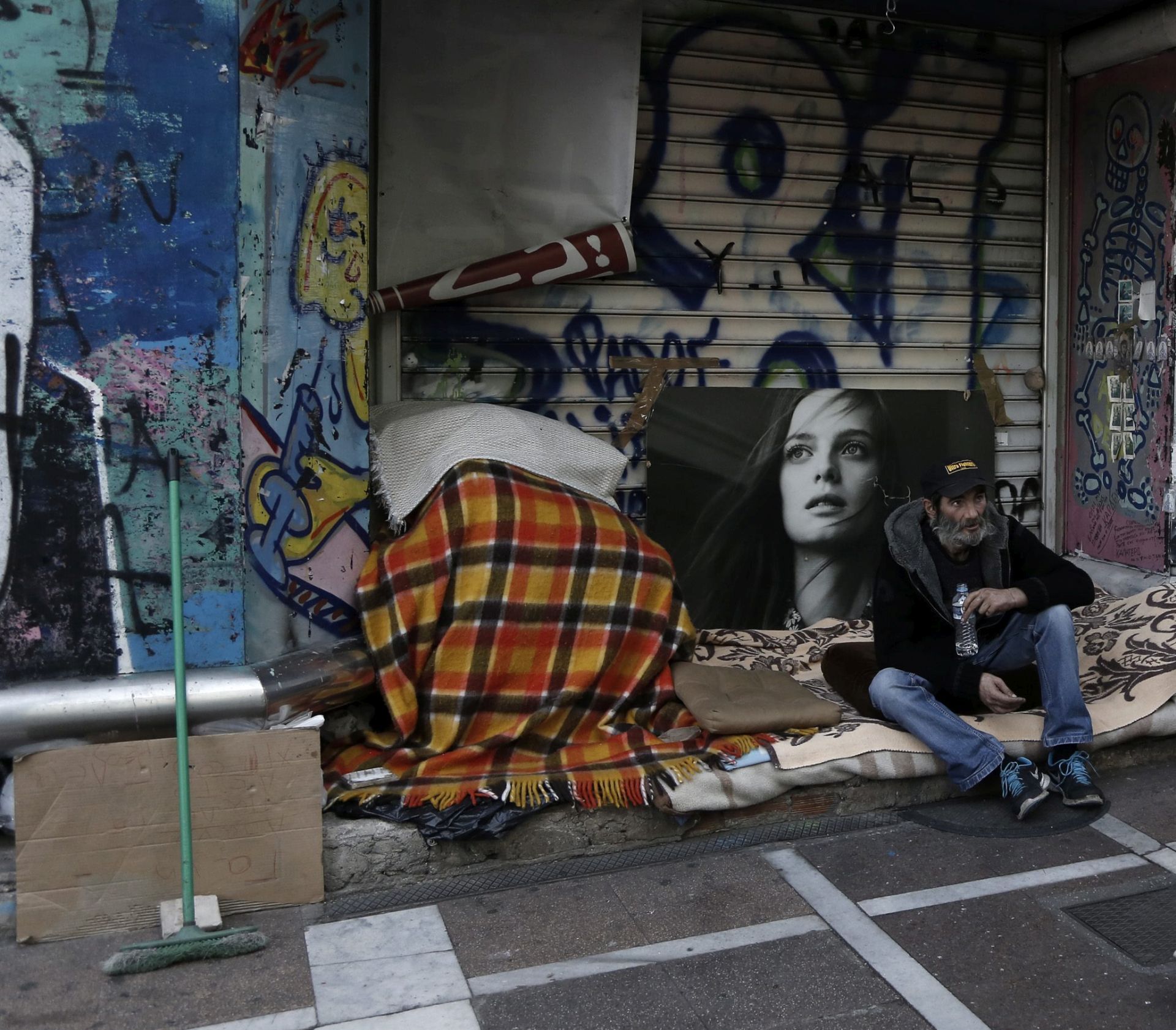 epa05067734 A couple walks in front of a homeless man in central Athens, Greece, 13 December 2015. Prime Minister Alexis Tsipras on 11 December underlined that the beginning of a discussion on a debt haircut will be a major national success and cited a Wall Street Journal report according to which the European Stability Mechanism (ESM) is examining options to ease Greece's debt burden and reduce its net present value by 52.5 percent.  EPA/YANNIS KOLESIDIS