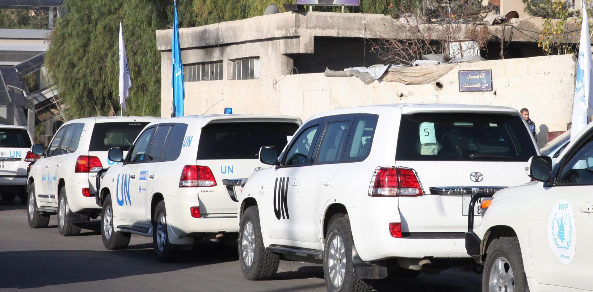 epaselect epa05101470 UN vehicles accompanying several trucks loaded with food, medicine, blankets and other materials drive past a poster depicting Syrian president Bashar al-Assad as they head to the besieged town of Madaya, some 24 kilometers southwest of Damascus, Syria, 14 January 2016. Convoys of humanitarian supplies, the second in a week, were on their way to three besieged Syrian towns. Some 44 trucks will enter the rebel-held town of Madaya near the capital Damascus and 17 others will enter the government-controlled towns of Foua and Kefraya in north-western Syria, the International Committee of the Red Cross (ICRC) said. Reports of starvation in Madaya, a mountain town near the Lebanese border, had triggered a global outcry. The aid deliveries were arranged under a UN-sponsored deal between government and rebel forces.  EPA/YOUSSEF BADAWI
