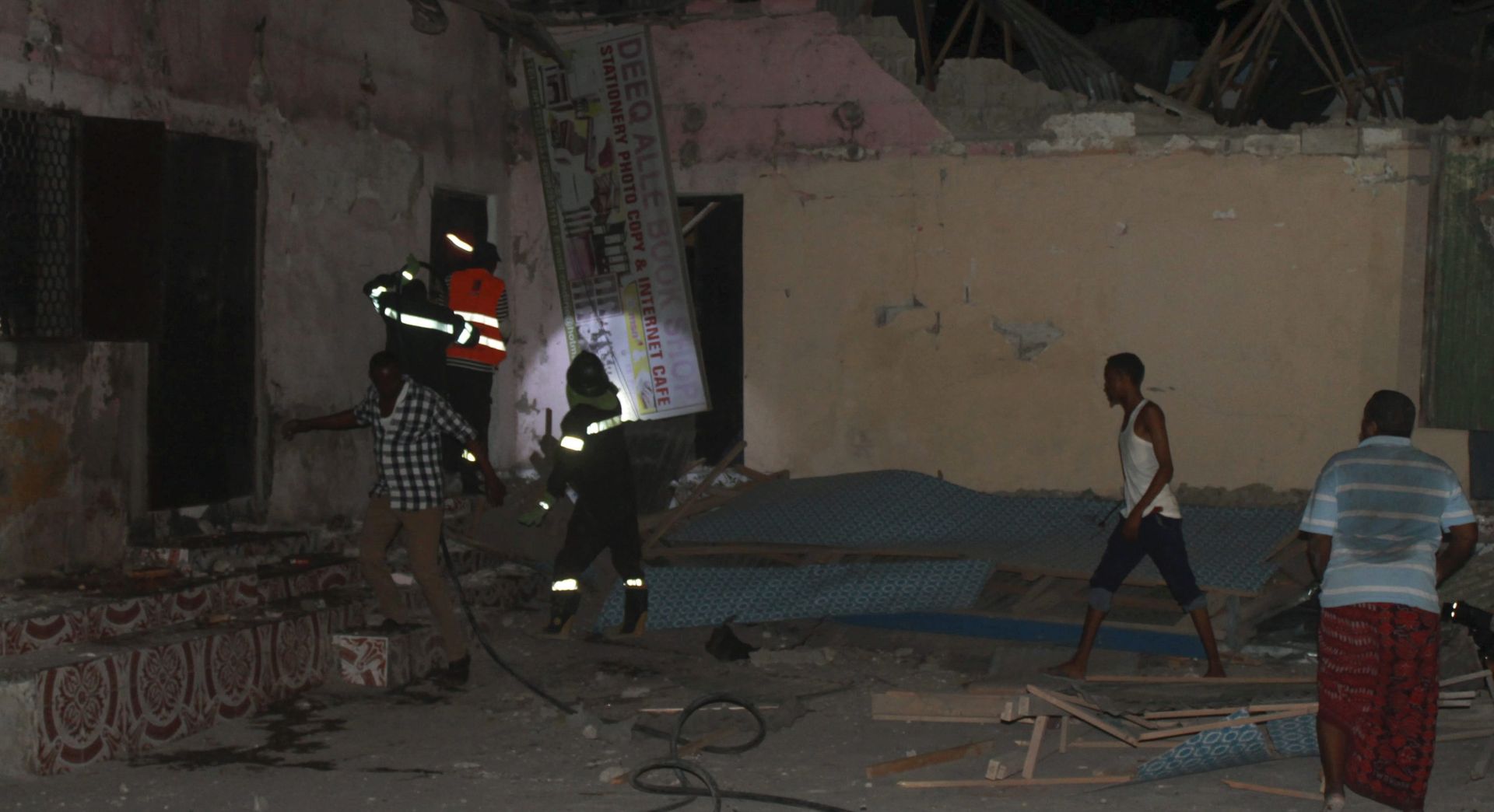 epa05182533 People search for victims at the scene of an attack in front of the SYL hotel in Mogadishu, Somalia, 26 February 2016. Gunmen from Somalia's Islamist militant group al-Shabab allegedly detonated a car bomb at the entrance of the hotel and stormed the building, according to reports. A witness said at least 10 bodies were seen on the ground. The latest attack by al-Shabab comes a day after another attack in the city claimed by al-Shabab.  EPA/SAID YUSUF WARSAME