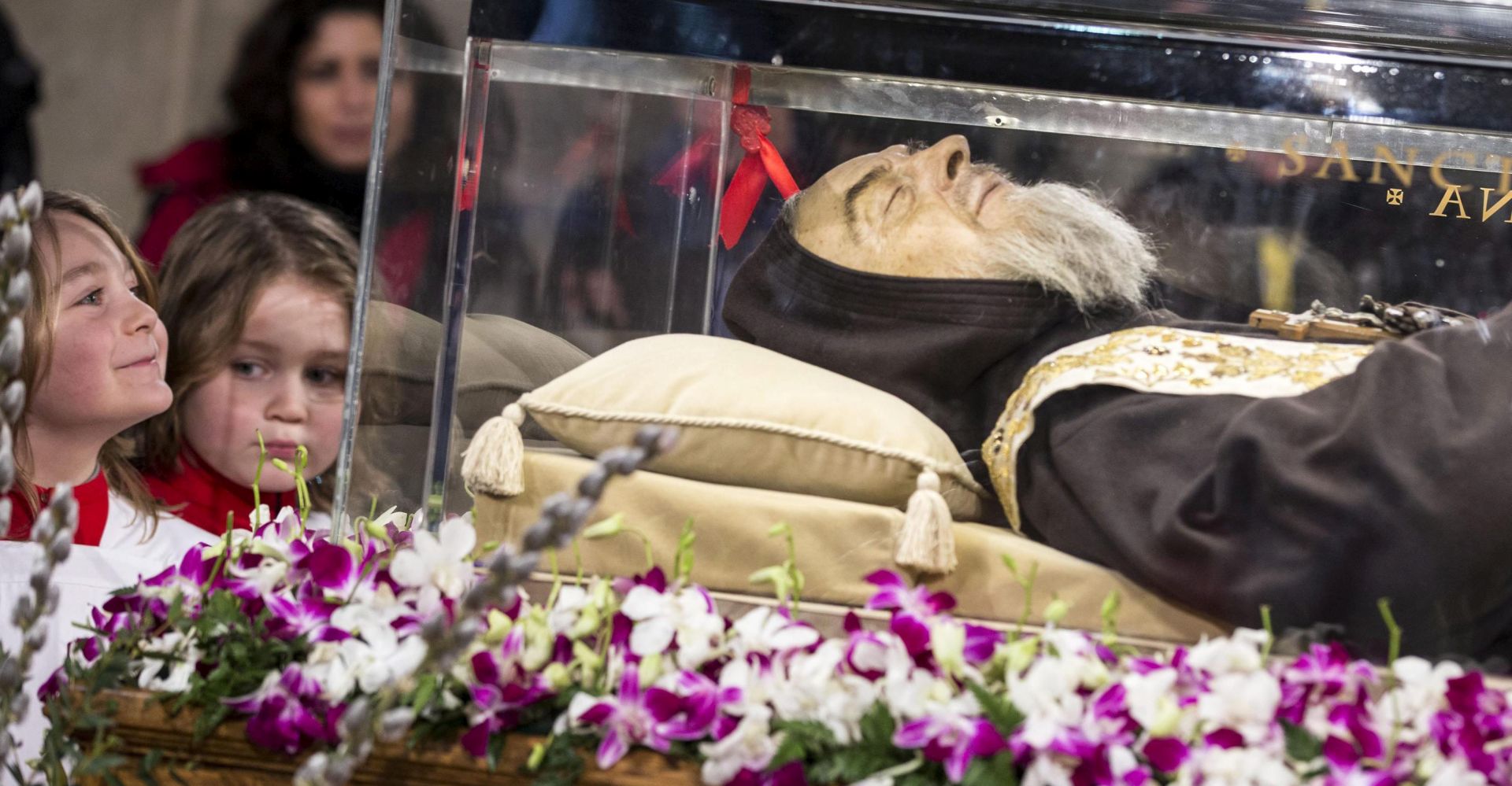 epa05141547 Young faithful watch the glass casket containing the remains of San Pio, better known as Padre Pio, as it arrives in Rome for a series of Jubilee events set up by Pope Francis, in Rome, Italy, 03 January 2016. The reliquary containing the saintly friar's body arrived at the basilica of San Lorenzo fuori le Mura, where a thousand faithful were awaiting for its arrival from his home town of Petralcina.  EPA/MASSIMO PERCOSSI
