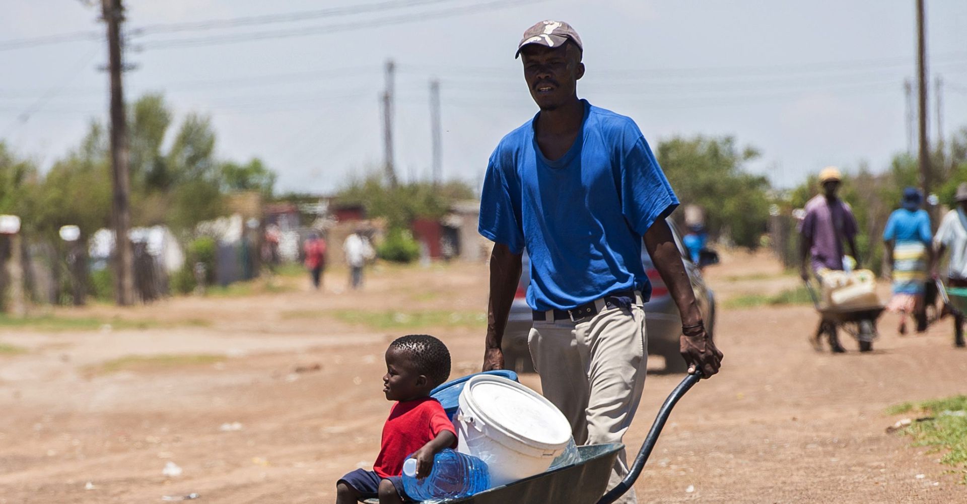 epa05152626 Residents push a wheelbarrow with water containers leaving a water distribution point in the rural farming town of Senekal, South Africa, 10 February 2016. The water is trucked to the town by local government sources. The town has had a severe water shortage for the past few months with residents having to queue for water at water hand out points. Large parts of this district and widespread areas of South Africa are experiencing the worst drought in 30 years as well as the highest temperatures in decades.  EPA/SHIRAAZ MOHAMED
