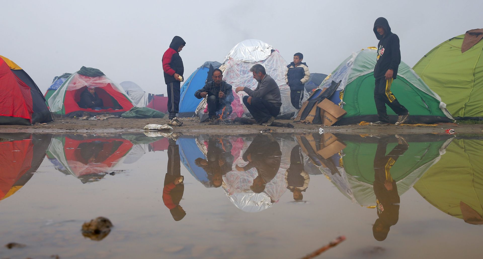 epa05200427 Refugees stand near tents as they wait to cross the Greek-Macedonian border near Idomeni, northern Greece, 08 March 2016. Thousands of people remained stranded in the refugee camp at Idomeni, on the Greek border with Macedonia, hours after the European Union and Turkey failed to reach agreement on resolving the migration crisis. Around 1,000 people are expected to disembark 08 March in the Athens' port of Piraeus and to continue north, toward Idomeni.  EPA/VALDRIN XHEMAJ
