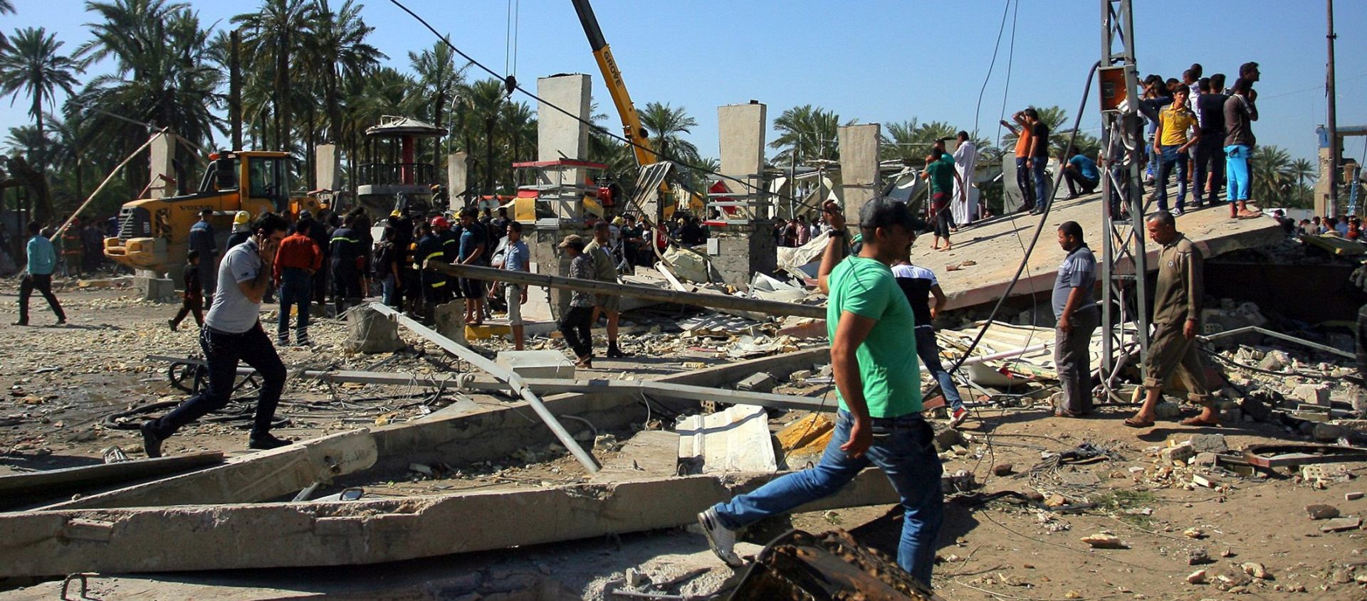 epa05197943 Iraqis gather at the scene of a truck bomb attack in Hilla, southern Baghdad, Iraq, 06 March 2016. At least 52 people, including security personnel and civilians, were killed in a suicide truck bombing claimed by the Islamic State terrorist militia. The explosion occurred when a suicide bomber rammed an explosives-packed fuel truck into a security checkpoint in the town of Hilla, some 100 kilometers south of the capital Baghdad.  EPA/KHIDER ABBAS