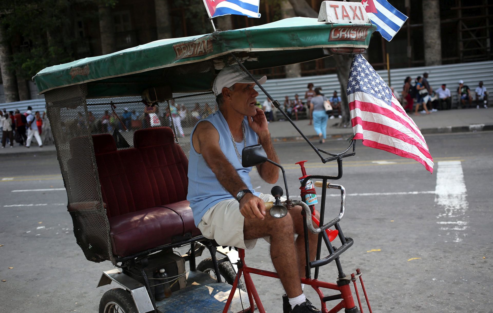 epa05213773 A man in a bici-cab adorned with American and Cuban national flags waits for costumers in Havana, Cuba, 15 March 2016. US President Barack Obama will visit Cuba from 20 to 22 March, and will be the first American president to do so in approximately 90 years.  EPA/ALEJANDRO ERNESTO