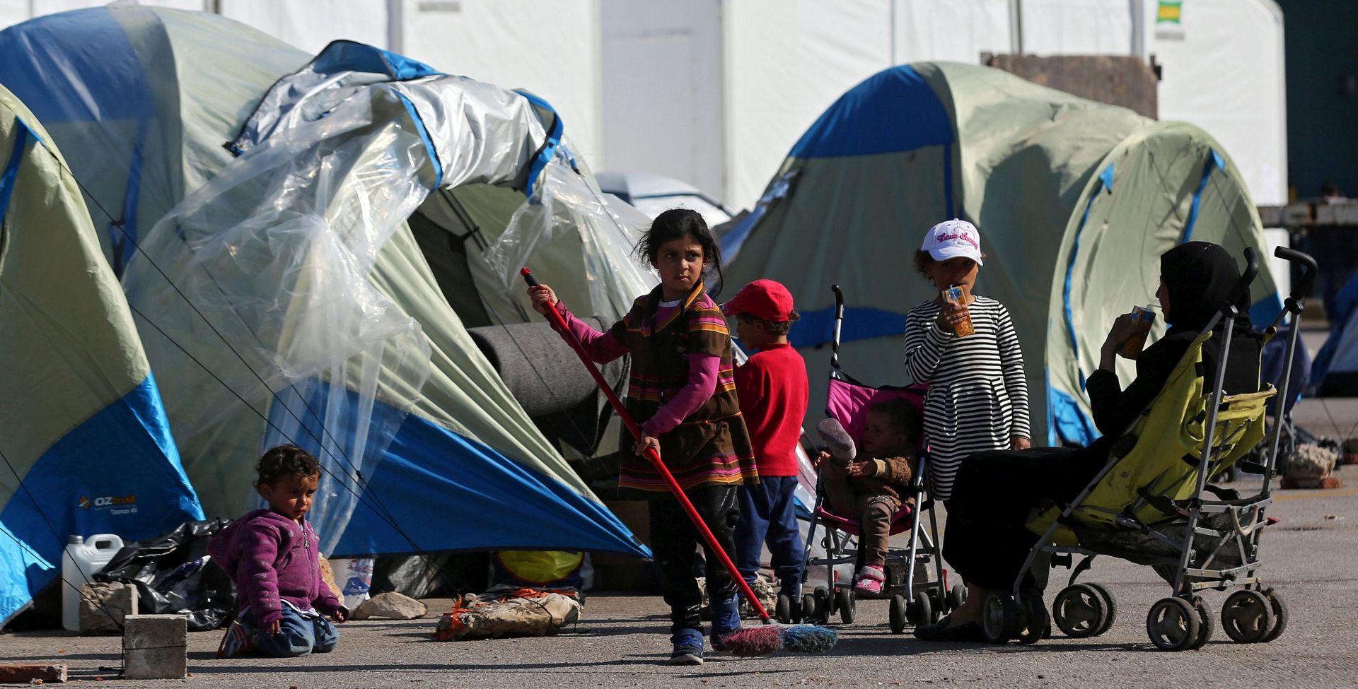 epa05236016 A refugee girl cleans the area outside the tent where she stays temporary with her family, in Piraeus, Greece, 30 March 2016. A total of 5,745 refugees and migrants are hosted at Piraeus port on 30 March 2016. Migration restrictions along the so-called Balkan route, the main path for migrants and refugees from Middle East to EU countries, have trapped thirty four thousands of them in Greece causing a humanitarian crisis.  EPA/ORESTIS PANAGIOTOU
