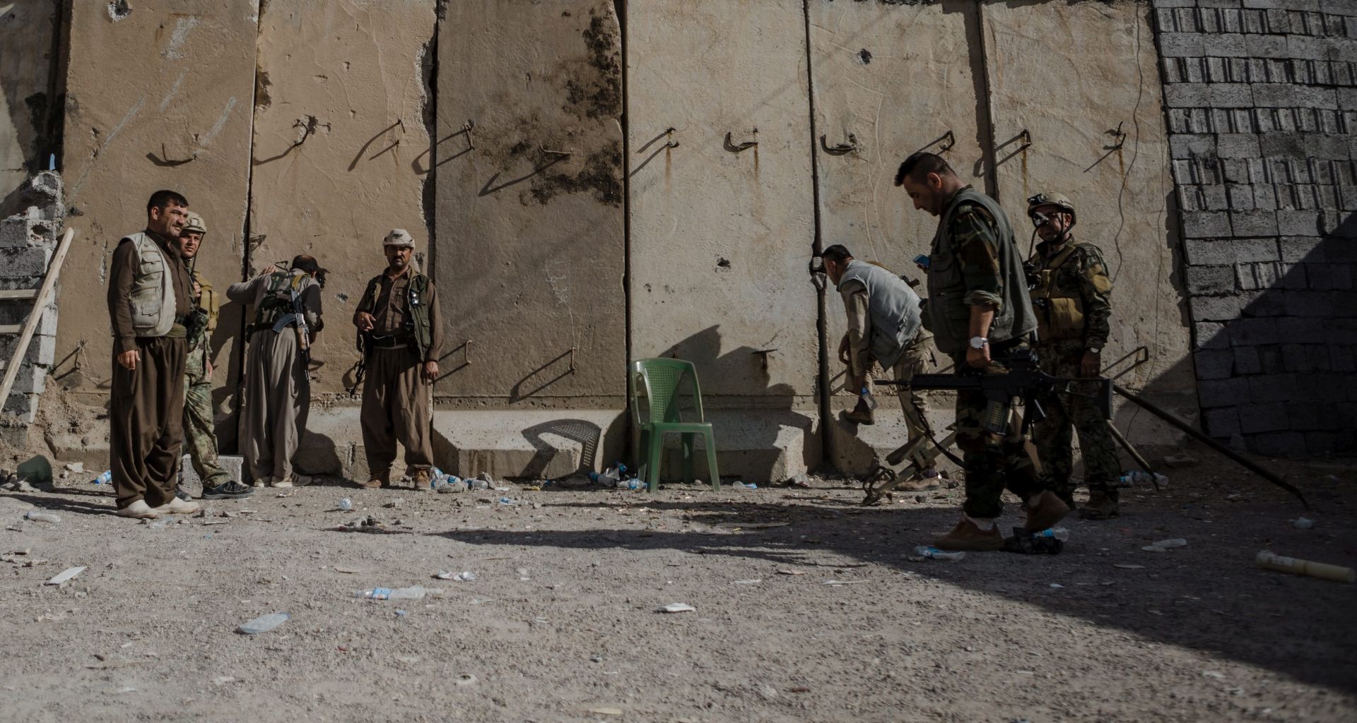 epa05279485 A photograph made available on 27 April 2016 shows Kurdish fighters standing in front of a wall separating Peshmerga fighters from Shiite militiamen positions in the city of Tuz Khurmatu, 175km north of Baghdad, Iraq, 26 April 2016. Local sources said clashes continued between the Kurdish Peshmerga and Shiite Hashed al-Shaabi militia for the third day despite calls for a ceasefire in the multi-ethnic city of Tuz Khurmatu. At least nine people were killed in the clashes that also cut the road between Baghdad and the oil-rich city of Kirkuk.  EPA/ANDREA DICENZO