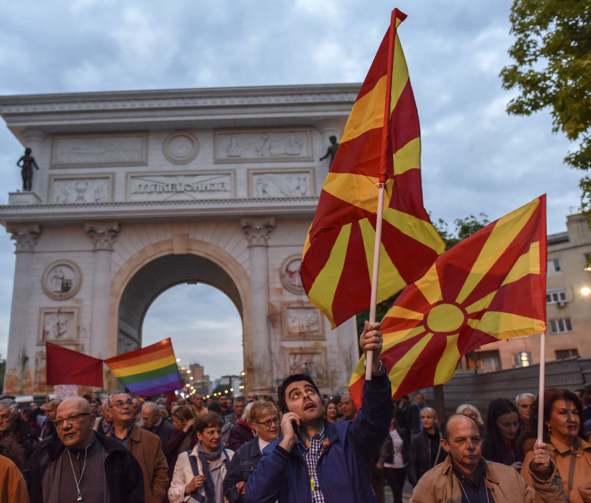 epa05312874 Protestors wave Macedonian flags as they pass under the Porta Macedonia, during the protest dubbed the 'Colorful Revolution' against Macedonian President George Ivanov's decision on wiretapping amnesty, in Skopje, The Former Yogoslav Republic of Macedonia, 17 May 2016. Daily protests in Macedonia have been ongoing for almost three weeks, after the President's decision to pardon dozens of politicians who were involved in a wiretapping scandal.  EPA/GEORGI LICOVSKI