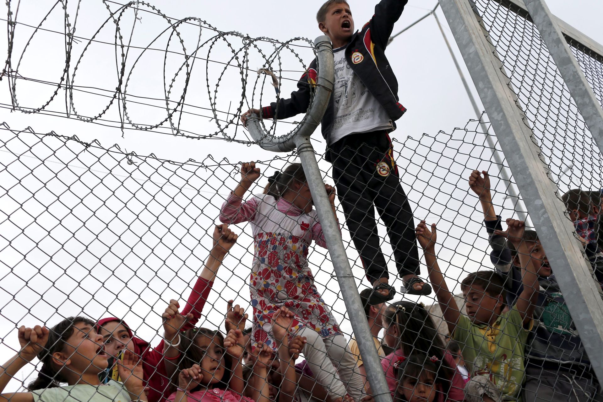epa05274071 Syrian refugee children stand at a fence after German Chancellor Angela Merkel, EU Council President Donald Tusk and Turkish Prime Minister Ahmet Davutoglu (none pictured) visited the refugee camp in Nizip district near Gaziantep, Turkey, 23 April 2016. Merkel travelled to Turkey with the President of the European Council, Donald Tusk, to get informed about the implementation of the EU-Turkey Refugee Agreement.  EPA/SEDAT SUNA