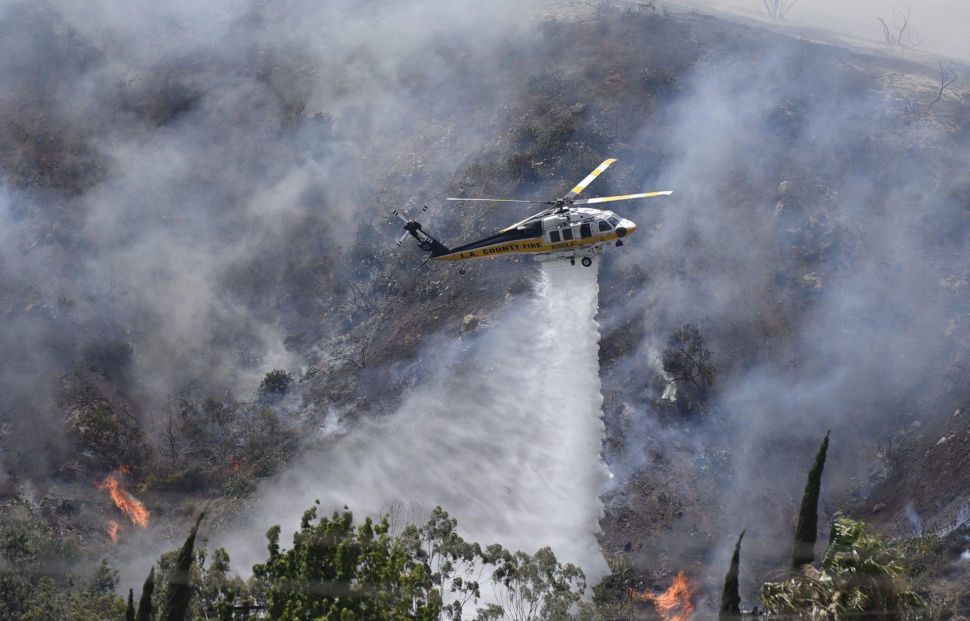 epa05380486 A fire fighting aircraft releases water as firefighters battle the thousand-acre plus 'Fish' wildland fire that erupted near the Angeles National Forest, Duarte, Califonia, USA, 20 June 2016. High temperatures over 100 degrees Fahrenheit (38 degrees Celsius) have hampered firefighting efforts throughout Southern California.  EPA/BOB RIHA JR.