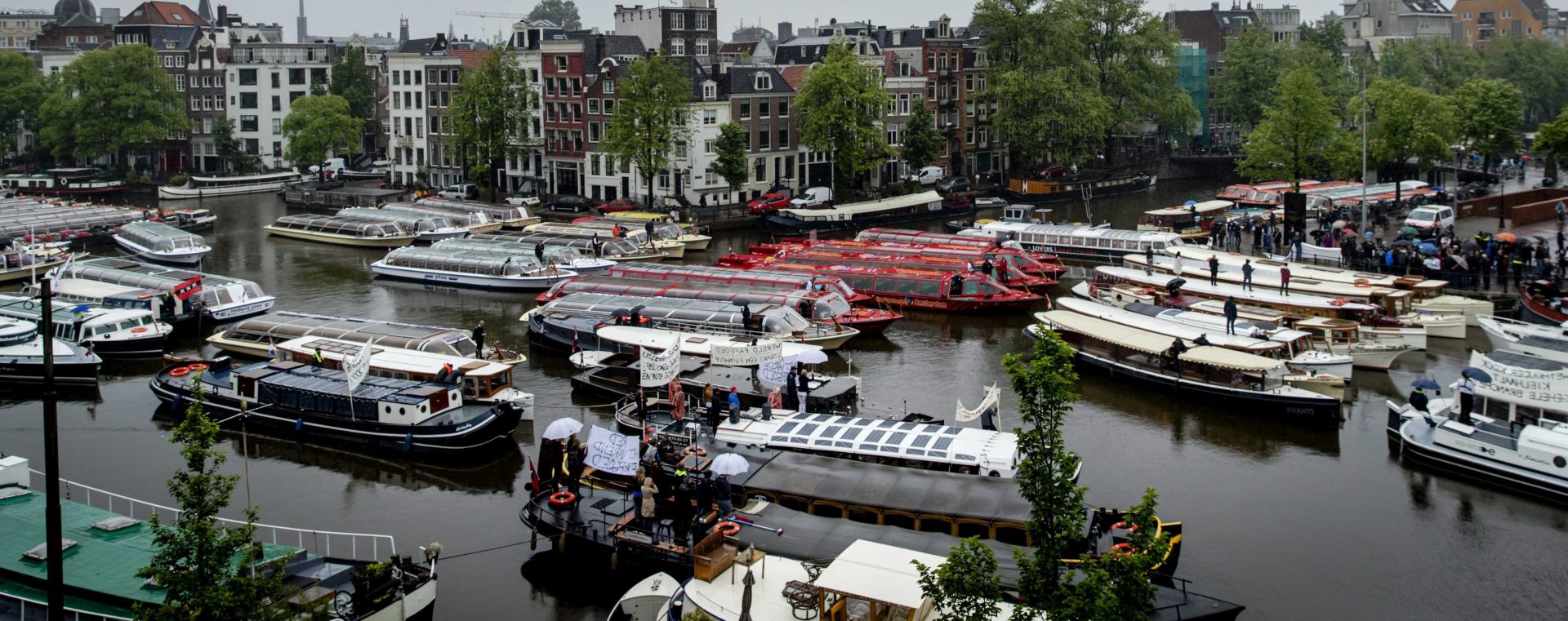 epa05379351 Sightseeing boats and canal boats demonstrate by blocking the canals of Amsterdam, The Netherlands, 20 June 2016. The occasion is the new policy of the municipality to ensure that all 135 boats over 14 meters will be banned from the canals.  EPA/ROBIN VAN LONKHUIJSEN