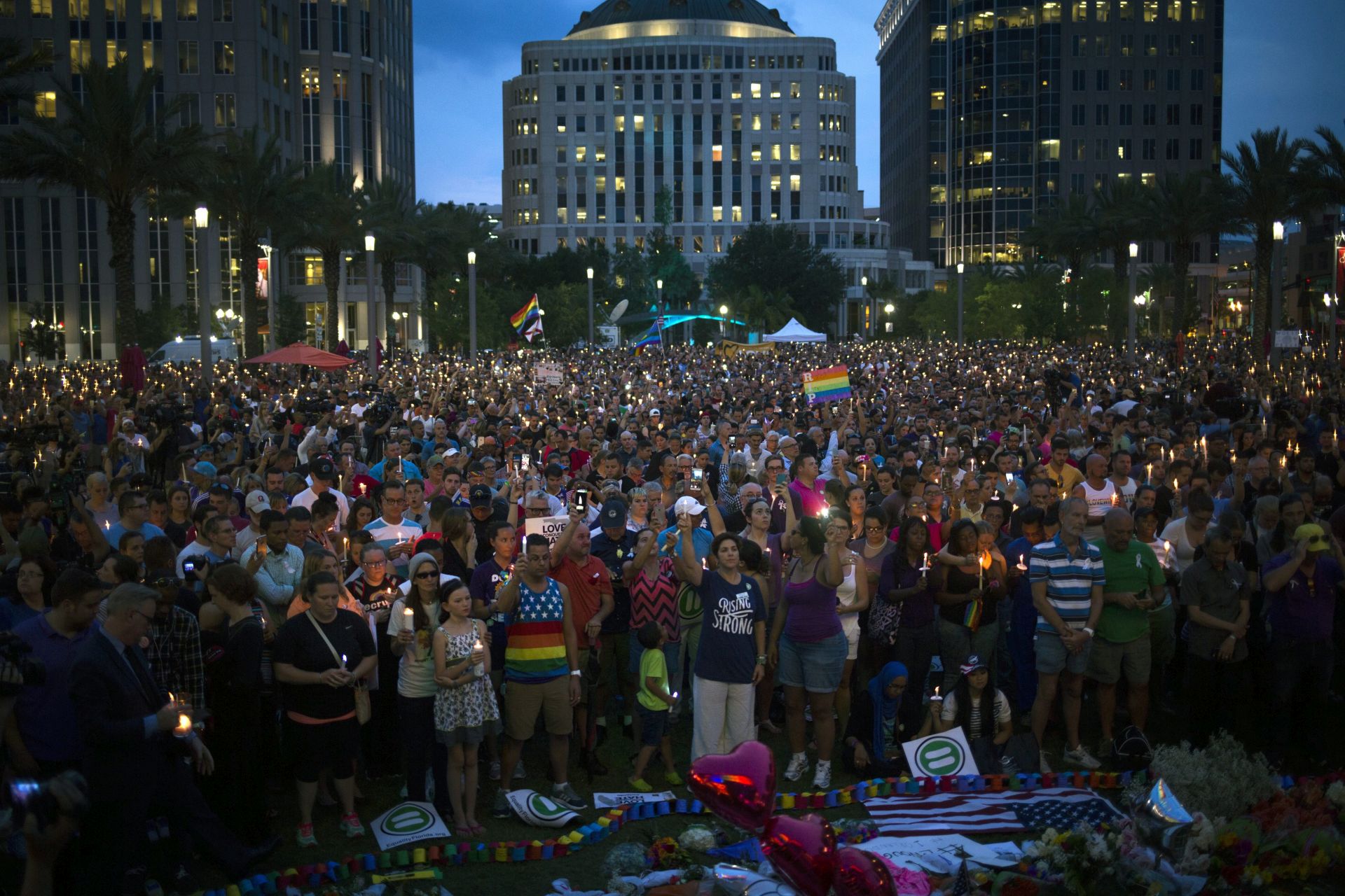 epa05363184 Hundreds of people gather at a candle light vigil outside of the Dr. Phillips Center for the Performing Arts to place tributes and flowers in honor to the victims of a mass shooting, in Downtown, Orlando, Florida, USA, 13 June 2016. A total of 50 people including the suspect were killed and 53 were injured in a shooting attack at an LGBT club in Orlando, Florida, in the early hours of 12 June. The shooter was killed in an exchange of fire with the police after taking hostages at the club.  EPA/JOHN TAGGART