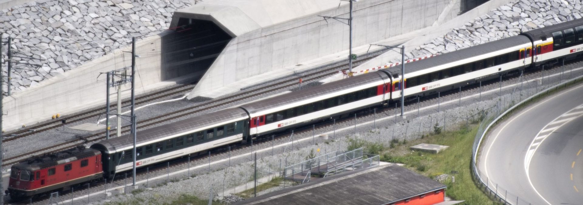 epa05338917 A train passes in front of the northern entrance of the Gotthard Base Tunnel on the eve of its inauguration, in Erstfeld, Canton of Uri, Switzerland, 31 May 2016. The Gotthard Base Tunnel, the world's longest railway tunnel, consists of two 57-kilometres-long single-track tunnels. The opening of the tunnel takes place on 01 June.  EPA/LAURENT GILLIERON