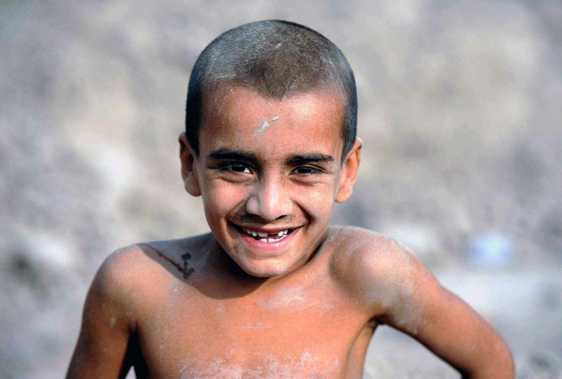 epa05450837 An Afghan boy poses for a photograph near his temporary shelter, in Jalalabad, Afghanistan, 01 August 2016. According to UN Assistance Mission in Afghanistan (UNAMA) report, 5166 civilian including 388 children casualties in Afghanistan hit a record high in the first half of 2016.  EPA/GHULAMULLAH HABIBI