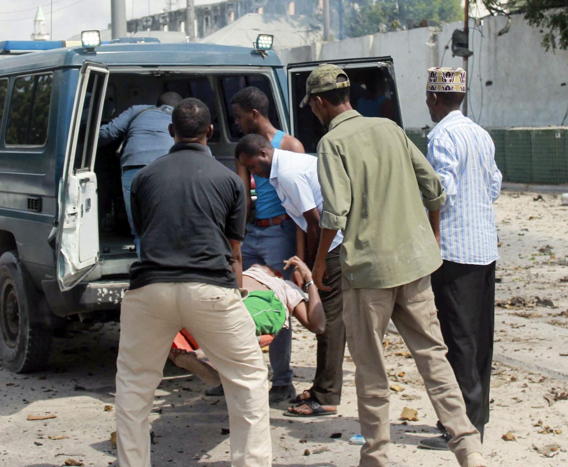 epa05449612 People carry a victim into the back of a van at the scene of a sucide attack in Mogadishu, Somalia, 31 July 2016. Explosions and gunfire were heard after attackers drove a car bomb into the Criminal Investigation Department (CID) headquarters in the capital Mogadishu, according to reports. The number of casualties are unknown. The country's Islamist militant group al-Shabab has claimed the responsibility for the latest attack.  EPA/SAID YUSUF WARSAME