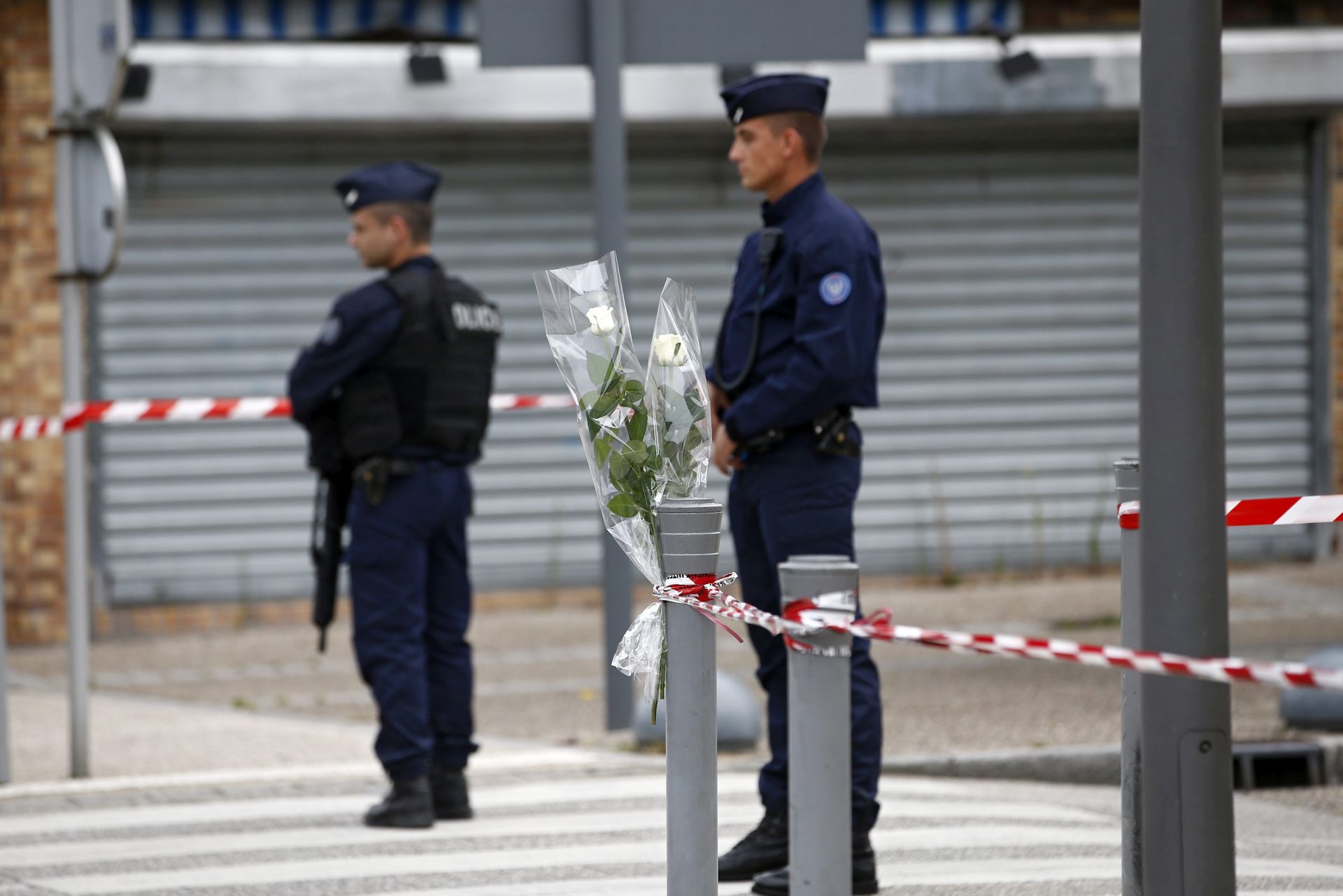 epa05443313 Police stands guard at a makeshift memorial near the Saint Etienne church where priest Jacques Hamel has been killed, in Saint-Etienne-du-Rouvray, near Rouen, France, 27 July 2016. According to reports, two hostage takers were killed by the police after they took hostages at a church in Saint-Etienne-du-Rouvray. One of the hostages, a priest was killed by one of the perpetrators.  EPA/IAN LANGSDON