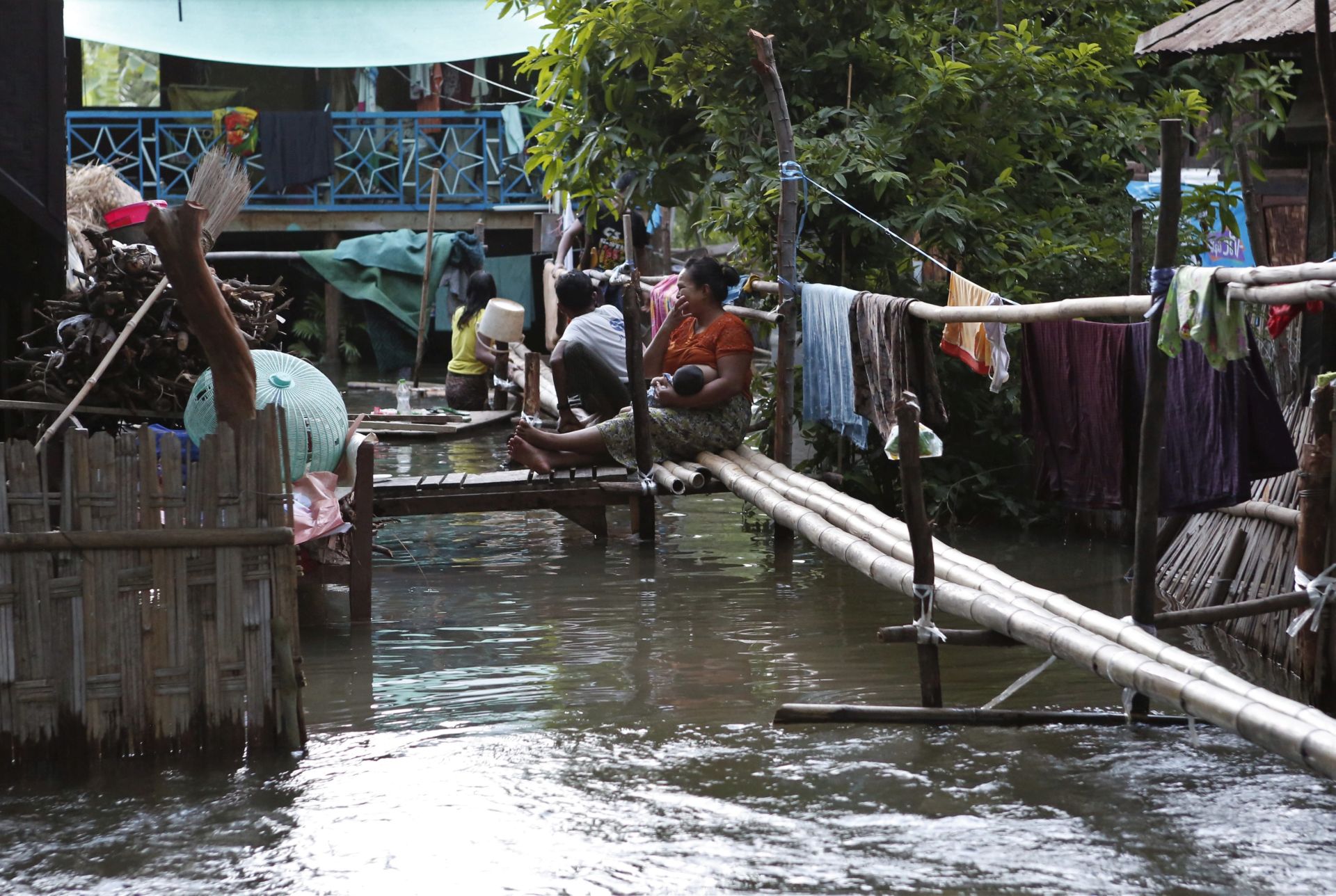 epa05452045 Myanmar people sits on the bamboo bridge flooding area of Tadaru Township, outskip of Mandalay, in Myanmar, 02 August 2016. Ayeyarwaddy river water in Mandalay passed the danger mark, flooding some villages in Amarapura township. Thousands of people from 16 villages has been affected and authority close the Yadanapon University in Amarapura township. Aids are needed for the people especially medicine and food.  EPA/HEIN HTET