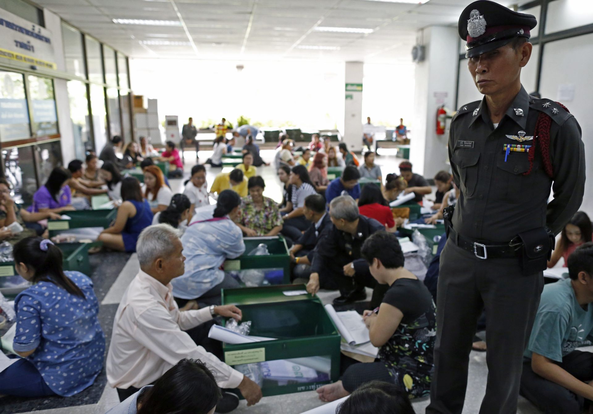 epa05458053 Thai policeman stands guard while electoral volunteer officials check and prepare ballot boxes and ballot papers in preperation for the referendum on a new constitution at Ratchathewi District Office in Bangkok, Thailand, 06 August 2016. Some 50.6 million Thai voters are eligible to cast their votes in a referendum for the controversial military's backed draft constitution on 07 August 2016.  EPA/RUNGROJ YONGRIT