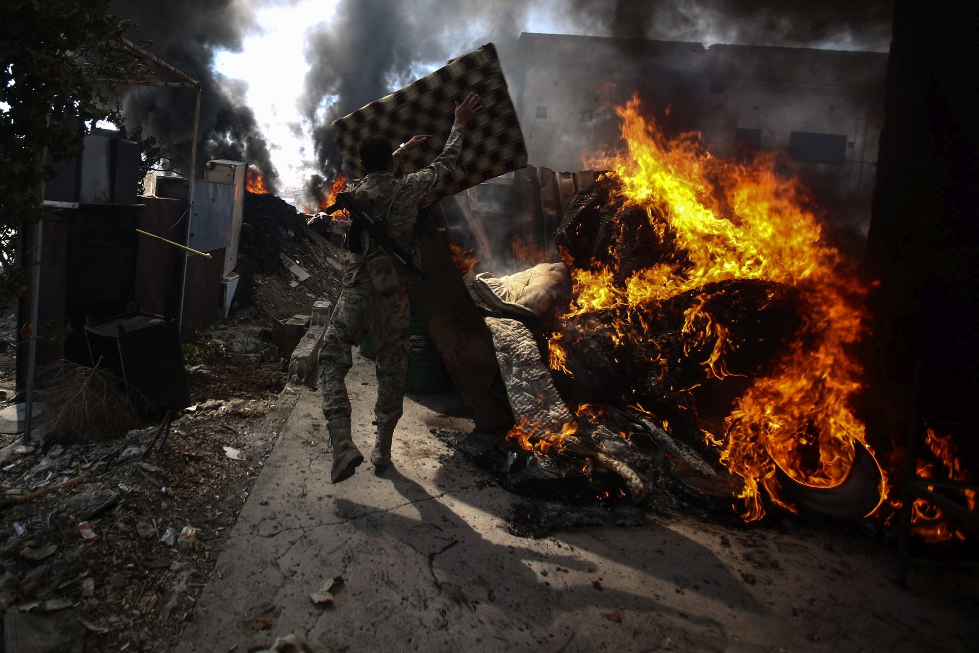 epa05525885 A Jaysh al-Islam fighter (Army of Islam) throws a cushion in the fire to keep the smoke clouds going at Tal al-Siwan area in the rebel-held city of Douma, outskirts of Damascus, Syria, 05 September 2016. Jaysh al-Islam fighters burn tyres, wool, and wood to create smoke clouds in order to blur and disturbe the line of site of snipers and scouts. Jaysh al-Islam, a militia fighting against the Syrian regime, captured Tal al-Siwan from Jaysh al-Tahrir (Liberation Army), a milita alligned with the Syrian regime, on 01 September 2016.  EPA/MOHAMMED BADRA