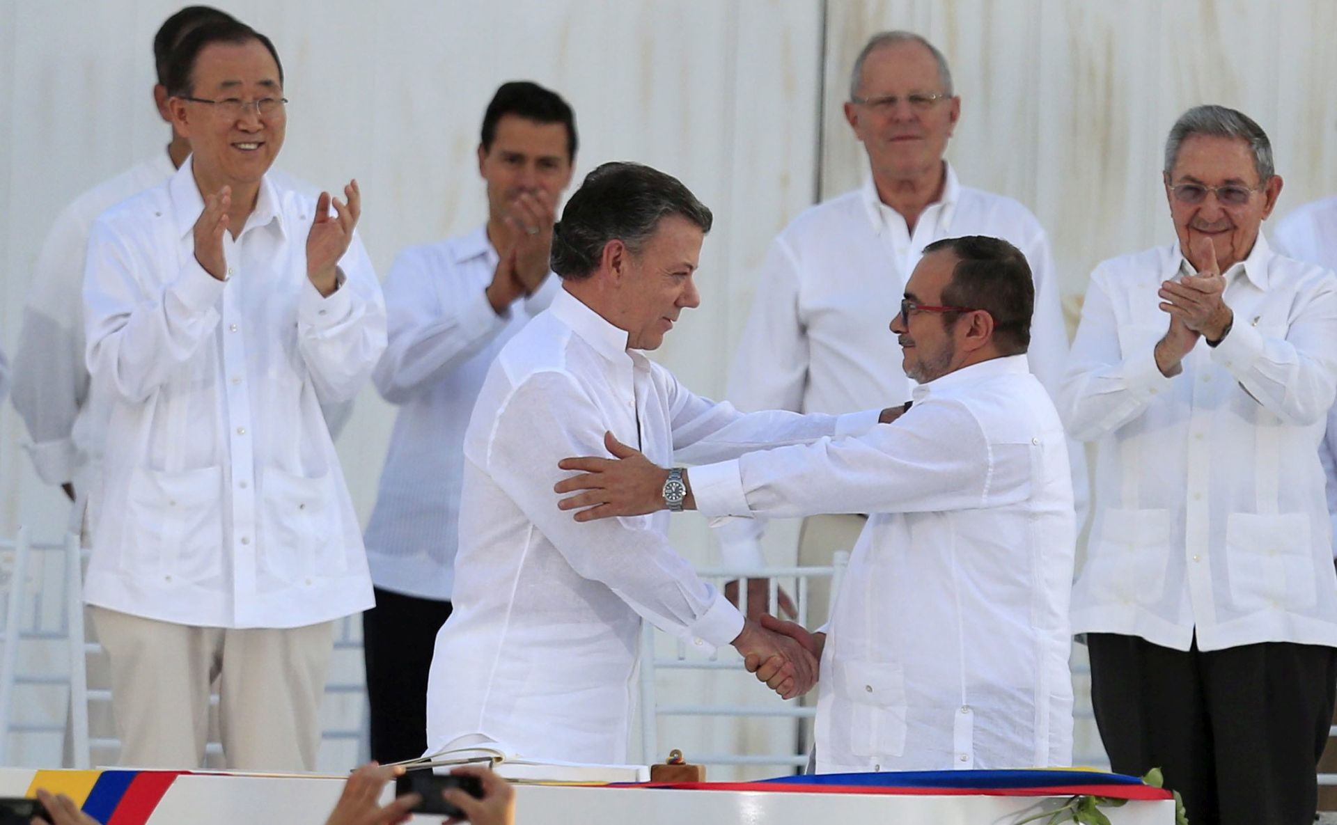epa05557534 Colombian President Juan Manuel Santos (3-L) and leader of the Revolutionary Armed Forces of Colombia (FARC) Rodrigo Londono Echeverri (R), alias 'Timochenko', shake hands after signing the peace agreement between Colombia's government and FARC to end over 50 years of conflict in Cartagena, Colombia, 26 September 2016. The pact is the result of nearly four years of talks in Havana and was signed at a solemn ceremony in Cartagena before more than 2,500 invited guests.  EPA/MAURICIO DUENAS CASTANEDA