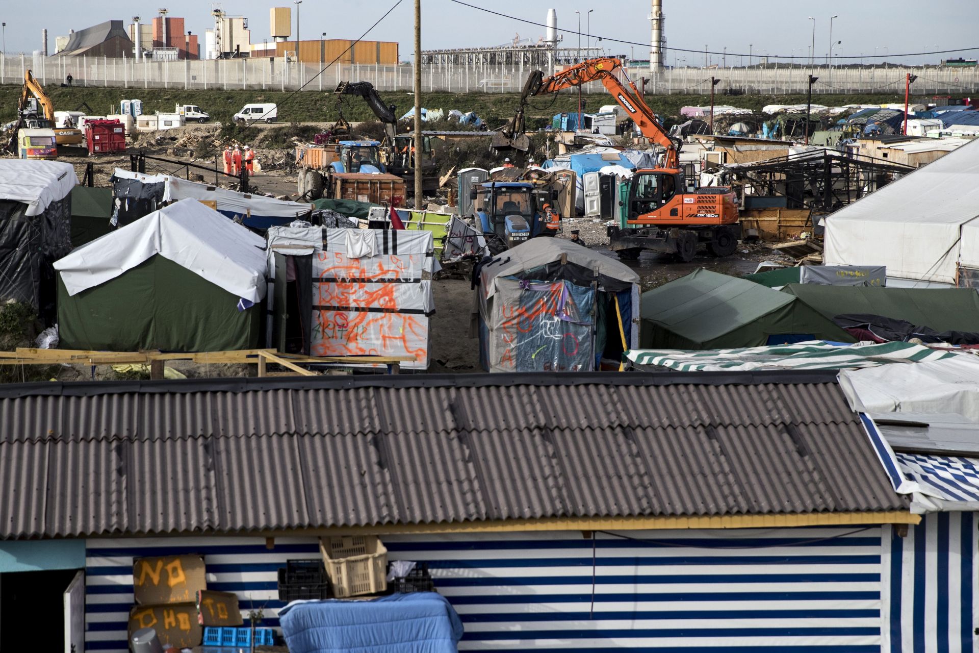 epa05605430 Workers continue to dismantle the makeshift camp 'The Jungle' in Calais, France, 27 October 2016. A large fire broke out the day before at the premises, burning a large part of the camp forcing the authorities to evacuate it. The camp gathering more than 7,000 migrants, was being dismantled for a fourth day by French authorities, a process that shall take about a week.  EPA/ETIENNE LAURENT