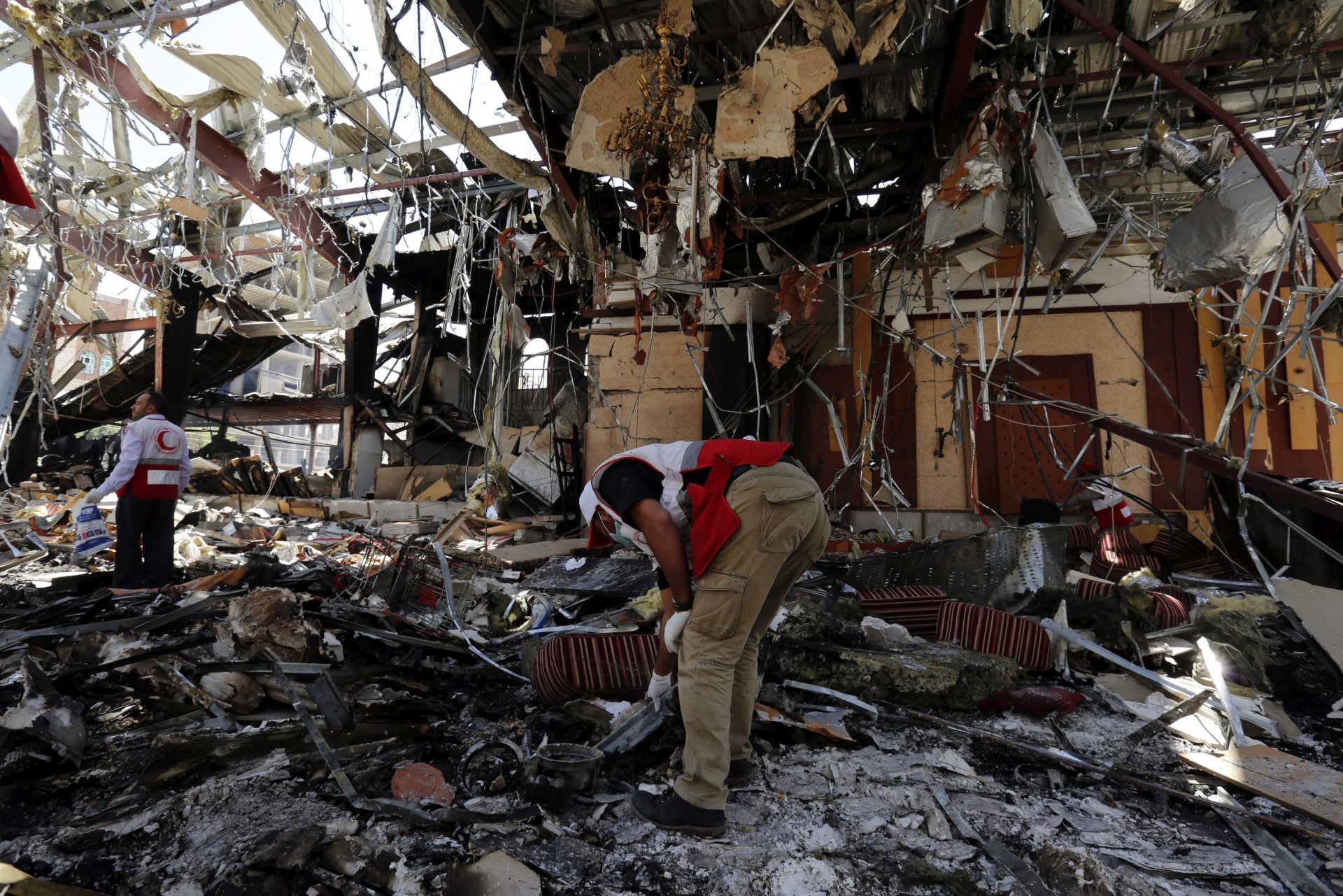 epa05578357 Members of Yemen Red Crescent Society look for remains of airstrikes victims inside the destroyed funeral hall a day after Saudi-led airstrikes targeted it, in Sanaa, Yemen, 09 October 2016. According to reports, the Saudi-led coalition warplanes targeted on 08 October a mourning ceremony at a community hall in the Yemeni capital Sanaa, killing over 140 Yemenis and wounding more than 525 others.  EPA/YAHYA ARHAB