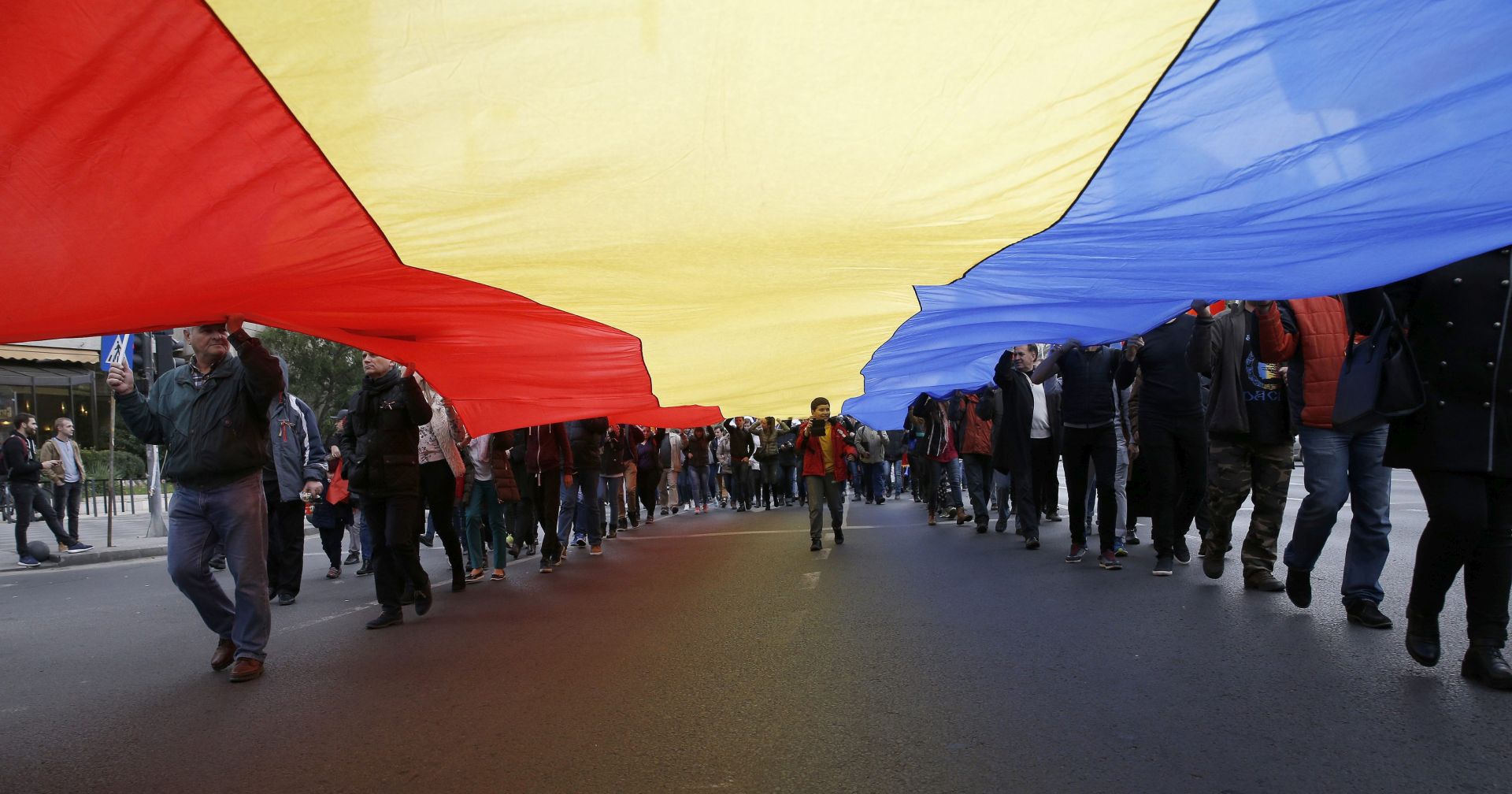 epa05597990 People hold a huge Romanian national flag during a march dedicated to the union between Moldova Republic and Romania, in Bucharest, Romania, 22 October 2016. About two thousand Romanian and Moldovan citizens gathered for a march, named 'The Fight for Basarabia' (Basarabia being the old name of Moldova Republic used before WWII) across the downtown of Romania's capital in a call to the states' governments to consider the unification of the two states. The official language of Moldova Republic is Romanian, and about 500,000 Moldovan citizens hold Romanian passports.  EPA/ROBERT GHEMENT