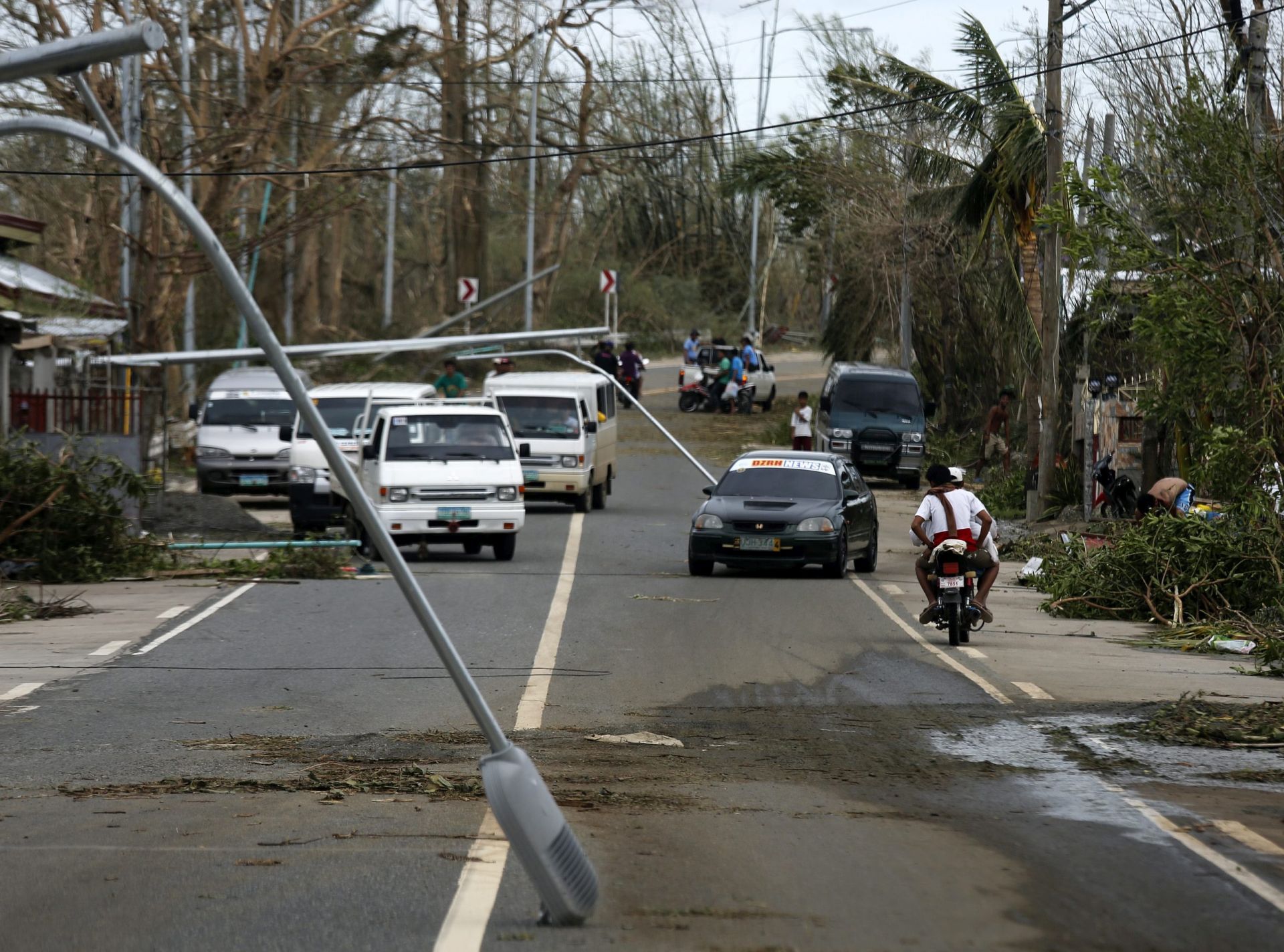 epa05593358 Filipino motorist maneuver between toppled light posts on a street in the typhoon-hit city of Tuguegarao, Cagayan province, Philippines, 20 October 2016. Many houses, trees, and electric posts were destroyed after Super Typhoon Heima made landfall in the Northern Philippines.  EPA/FRANCIS R. MALASIG