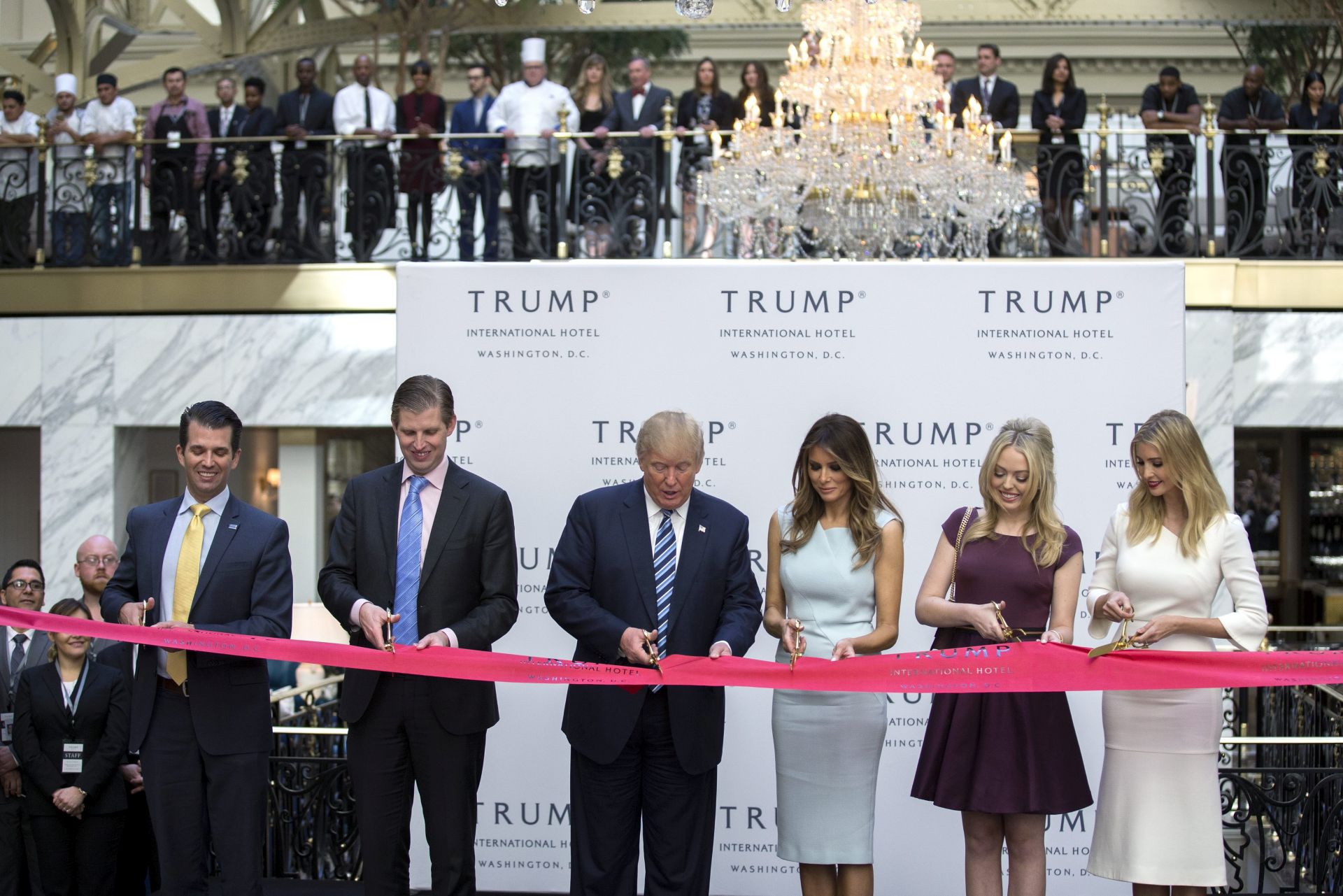 epa05604375 Republican Presidential nominee Donald Trump (3L), with sons Eric Trump (L) and Donald Trump Jr. (2L), daughters  Ivanka Trump (R) and Tiffany Trump (2R) and his wife Melania Trump (3R) participates in the ribbon cutting ceremony for the Trump International Hotel in Washington, DC, USA, 26 October 2016.  EPA/SHAWN THEW