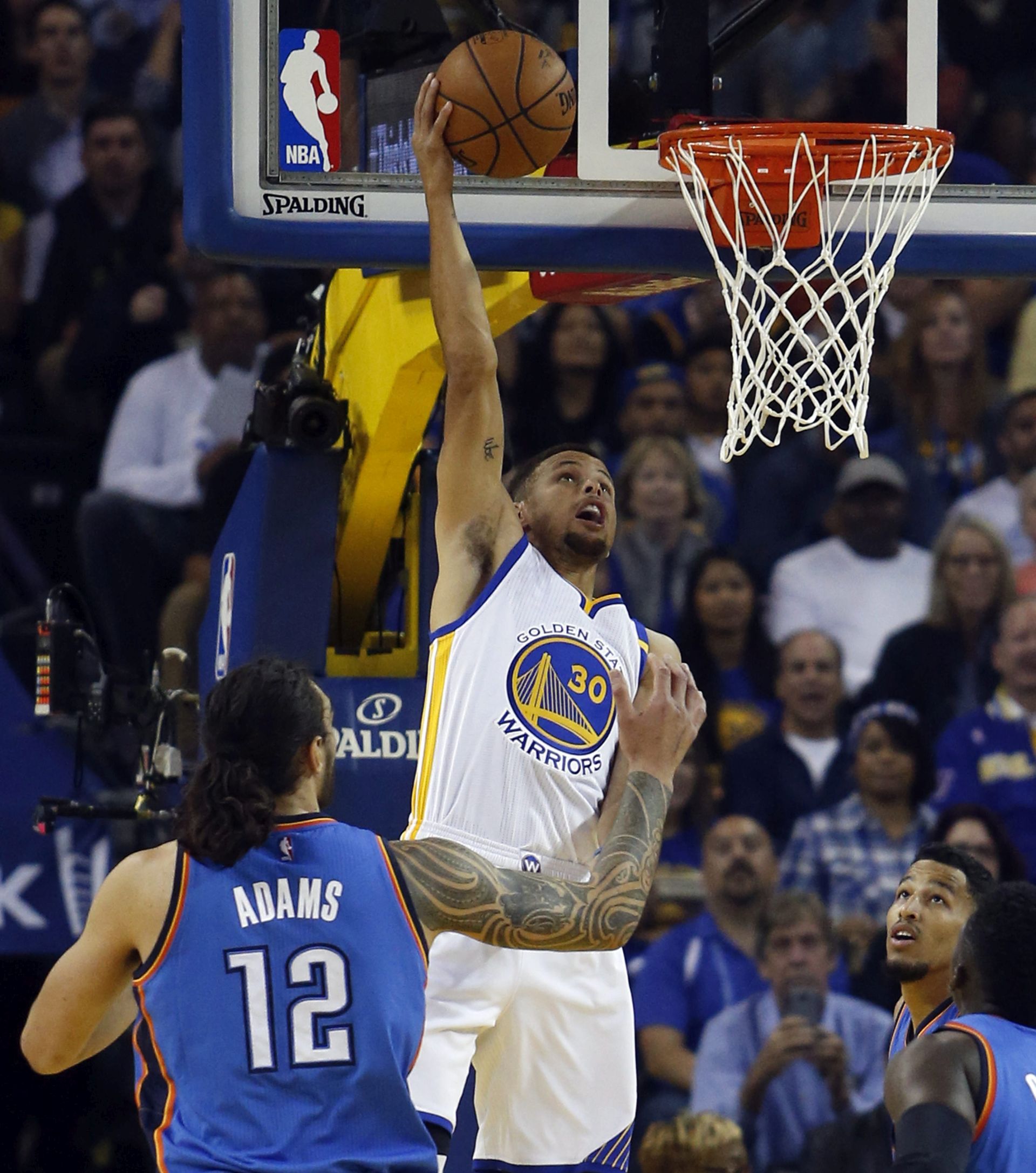 epa05617020 Golden State Warriors guard Stephen Curry (R) dunks the ball over Oklahoma City Thunder center Steven Adams of New Zealand (L) during the first half at Oracle Arena in Oakland, California, USA, 03 November 2016.  EPA/MONICA M. DAVEY