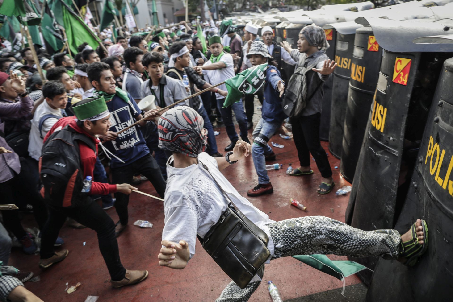 epa05617221 An Indonesian student kicks the anti police's shield during a protest against allegedly blasphemous remark made by Jakarta's Governor Basuki Tjahaja Purnama, popularly known as 'Ahok' outside the presidential palace in Jakarta, Indonesia, 04 November 2016. Thousands of protesters staged a rally demanding the Jakarta's governor to be prosecuted for blasphemy.  EPA/MAST IRHAM