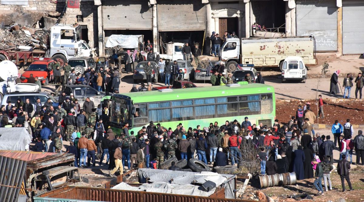 epa05677110 A handout photograph released by the official Syrian Arab News Agency (SANA) showing people standing near a government green bus during evacuation of fighters and their families from rebel-held zones in Aleppo, Syria, 15 December 2016. The evacuation of Aleppo began on 15 December as the first ambulances and buses extracted the sick and wounded from final rebel-held zones in the northern Syrian city, the Red Cross NGO said. Reports state the first batch of 951 gunmen and their families were evacuated via al-Ramouseh crossing to Aleppo southwestern countryside.  EPA/SANA HANDOUT  HANDOUT EDITORIAL USE ONLY/NO SALES