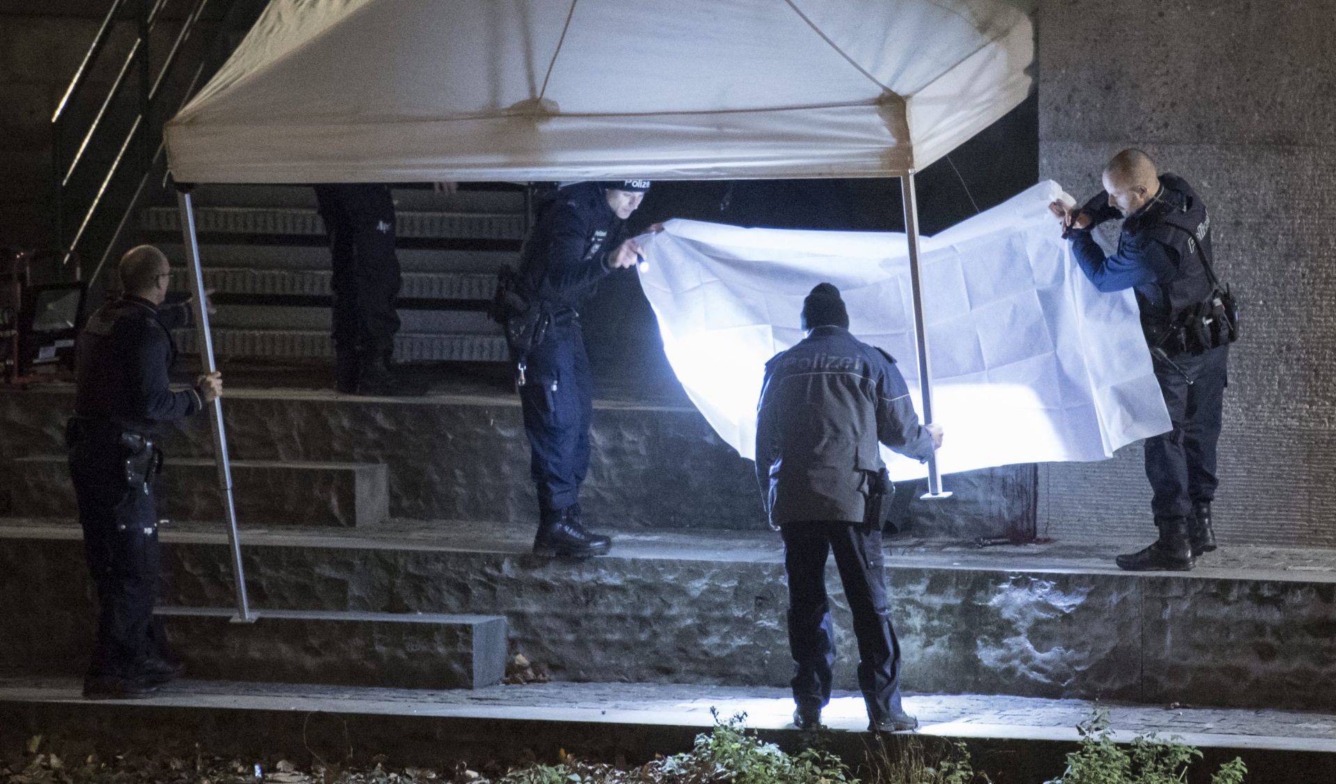 epa05682672 Policemen inspect the site where a body is found under the Gessnerbruecke bridge, after the shooting attacks at the Islamic center in Zurich, Switzerland, 19 December 2016. Three people were injured at the shooting near Zurich's main railway station. According to the police, the attackers are still on the run.  EPA/ENNIO LEANZA