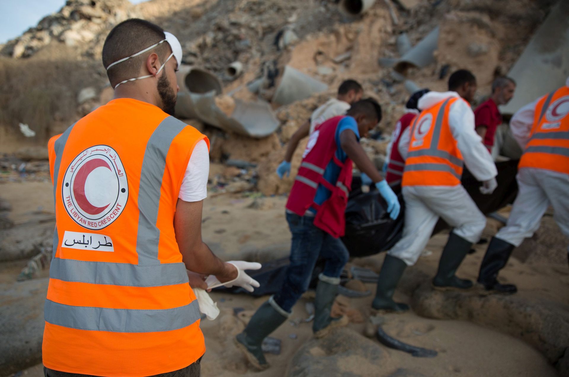 epa05619367 Libyan Red Crescent members carry a deceased migrants body away from the beach as they recover the bodies of drowned migrants who washed ashore, in Janzour city, Tripoli, Libya, 05 November 2016. According to a Red Crescent official, the Red Crescent has recovered 41 bodies of migrants since 29 October 2016.  EPA/STR ATTENTION EDITORE: GRAPHIC CONTENT