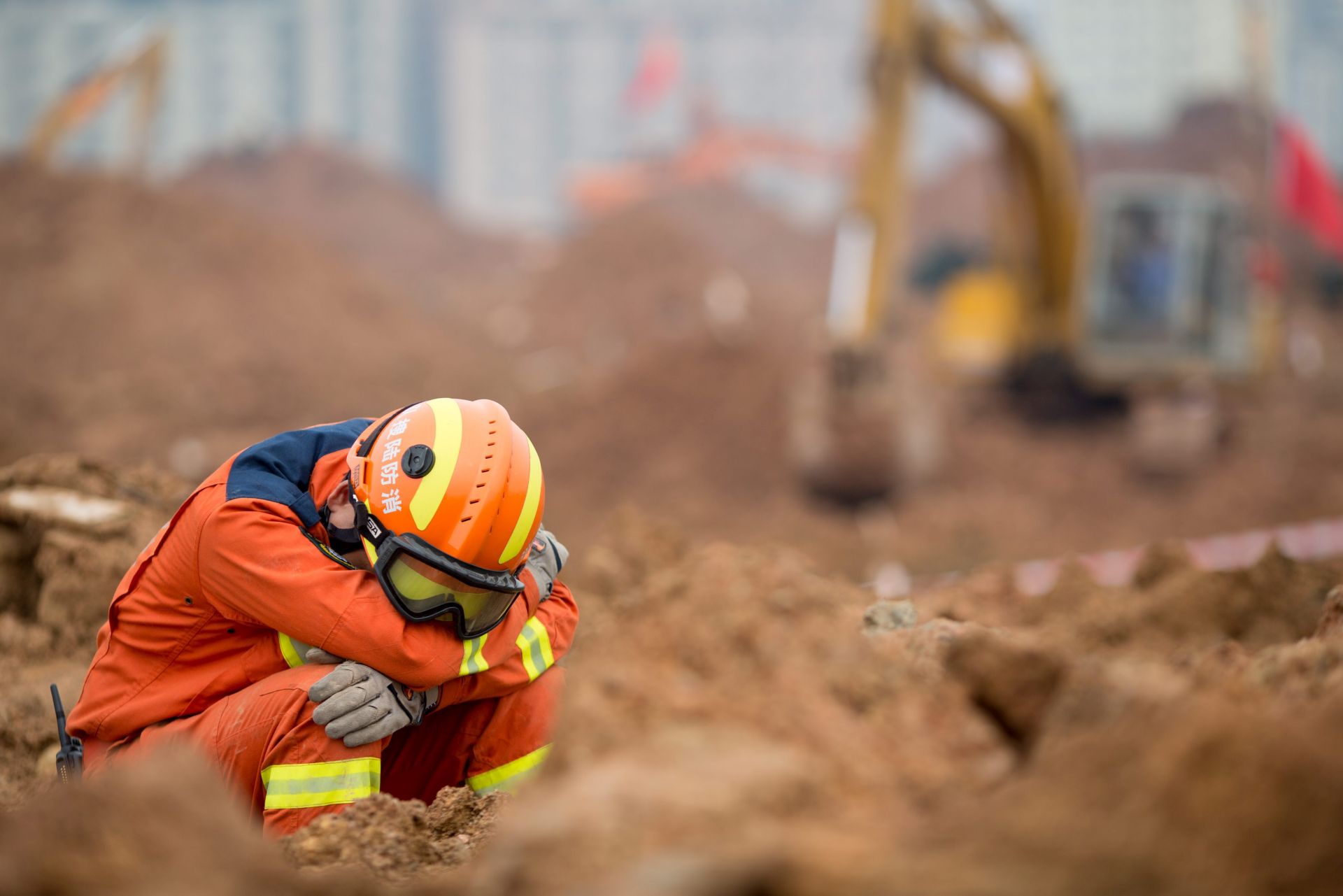 epa05077731 An exhausted rescuers takes a rest as he sits among mud and rubble after a landslide in Shenzhen, south China's Guangdong province, 21 December 2015. The search intensified for more than 91 people missing in southern China after a massive landslide buried around three dozen buildings in the city of Shenzhen. The number of rescue workers was boosted by around 1,200 to just over 2,900, the Xinhua news agency reported. Another 78 excavators arrived to help dig through 380,000 square metres of silt up to 10 metres deep, the deputy mayor of Shenzhen, told a press conference on 21 December. The landslide occurred when a large, unstable mound of dumped earth and construction rubbish collapsed, the Ministry of Land and Natural Resources said  EPA/FREDDY CHAN
