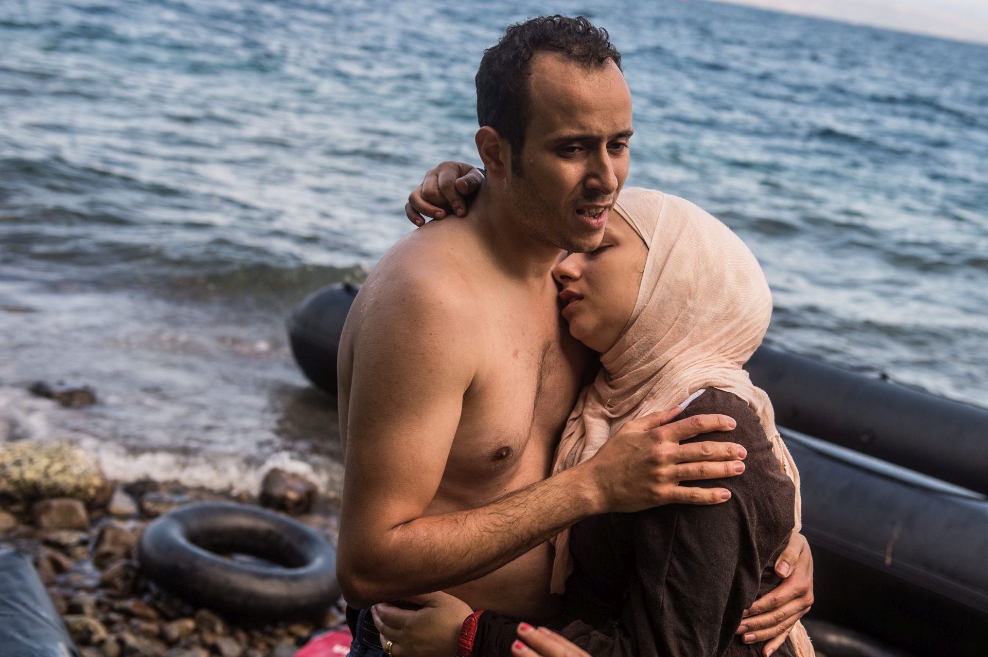 epa04960218 A migrant hugs his pregnant wife after making land from an overloaded rubber dinghy as they arrive on the coast near Skala Sikaminias, Lesbos island, Greece, 02 October 2015. An estimated 100,000 refugees and migrants arrived on the Greek islands during August, according to the Hellenic Coast Guard.  EPA/FILIP SINGER