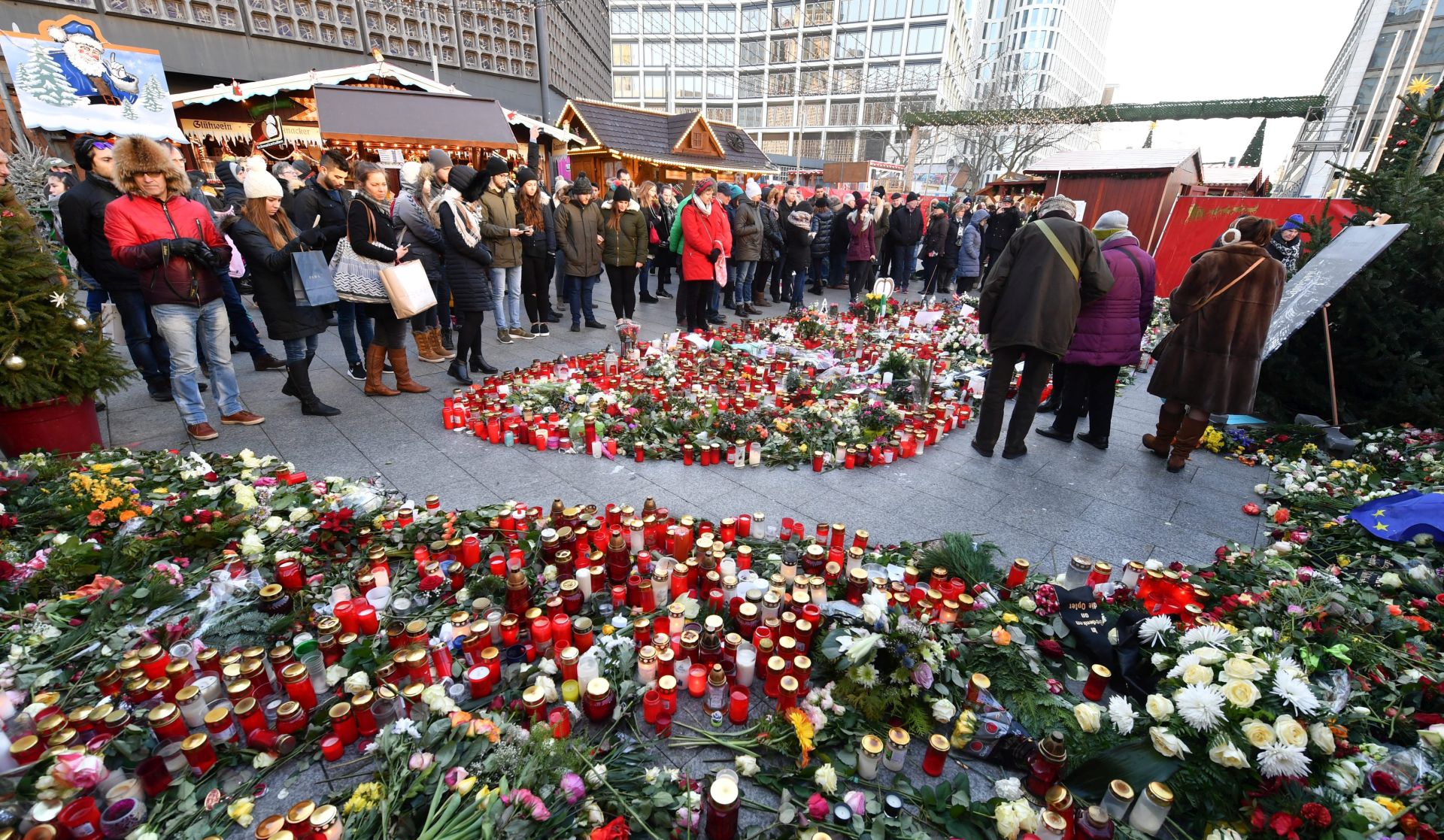 epa05692633 Candles and flowers are placed on Breitscheidplatz square at the Memorial Church in Berlin, Germany, 31 December 2016. At least 12 people were killed and around 50 injured in the evening of 19 December 2016, when a truck was driven into a Christmas market, in what authorities said was a deliberate attack.  EPA/JENS KALAENE