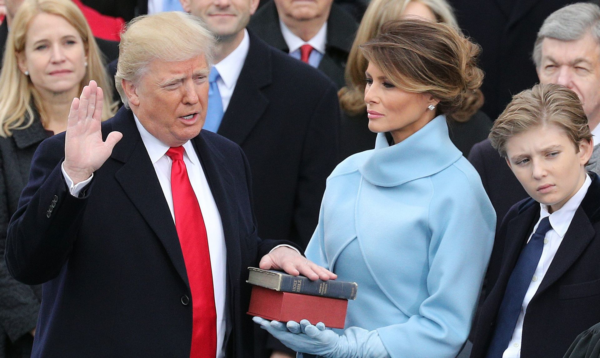 epa05735429 President-elect Donald J. Trump (L) takes the oath of office as the 45th President of the United States in Washington, DC, USA, 20 January 2017. Trump won the 08 November 2016 election to become the next US President. On right is his son Baron and his wife Melania (2-R) holding a bible as he takes tha oath.  EPA/JUSTIN LANE