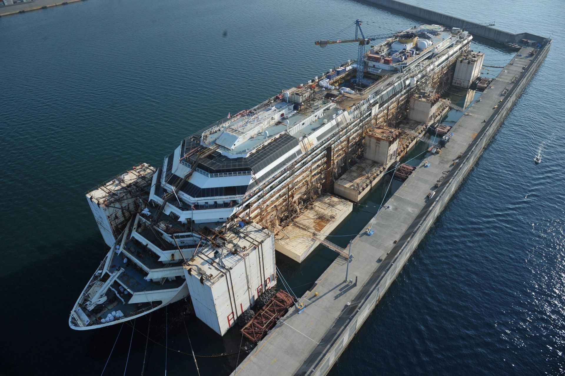 epa04431318 An image taken from a helicopter shows the cruise ship Costa Concordia docked at the port of Genoa Voltri, Genoa, Italy, 04 October 2014. The Costa Concordia is in Italy's historic port city Genoa for scrapping, two-and-a-half years after 32 people died when it ran aground off the island of Giglio. Its dismantling in the waters off the northern city of Genoa is expected to last two years and employ almost 1,000 people. About 40,000 to 50,000 tons of steel are expected to be recycled from the wreck.  EPA/LUCA ZENNARO