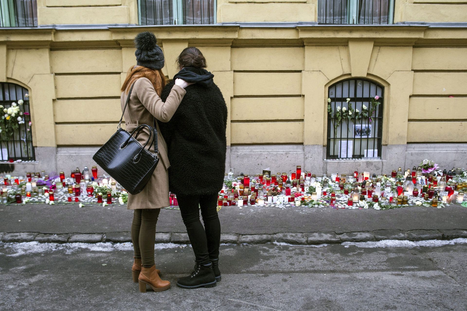 epa05743965 A survivor (R) is embraced by another girl as they stand at a makeshift memorial outside Szinyei Merse Pal Secondary School to pay tribute to victims of the crash of a Hungarian bus in Italy, in Budapest, Hungary, 23 January 2017. Hungary observes a day of national mourning after a bus carrying Hungarian secondary school students from France back to Hungary crashed on a highway near Verona, Italy on 20 January killing 16 and injuring 26 people.  EPA/BEA KALLOS HUNGARY OUT