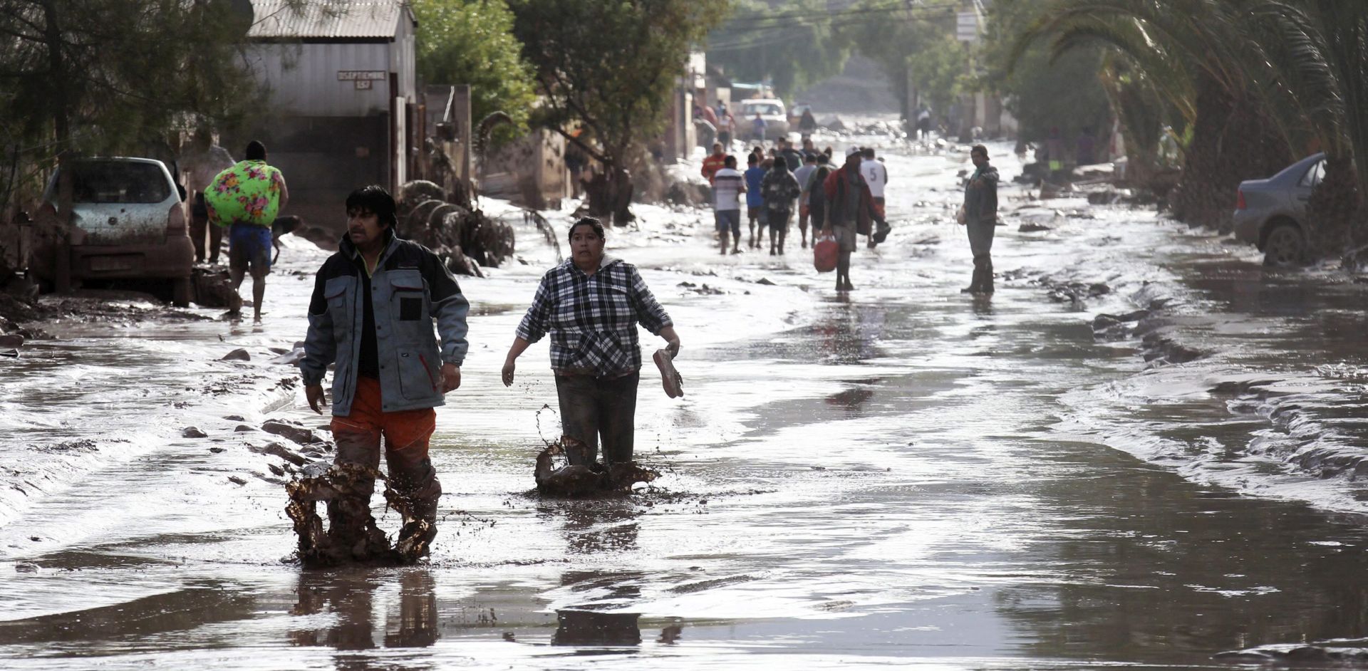 epa04680106 People walk along a street after a flood in Copiapo, Chile, 26 March 2015. The Chilean government declared a state of emergency on 25 March in Antofagasta, Tierra Amarilla, Alto del Carmen and Copiapo. The government said on 26 March that four people had died as a result of torrential rains and flooding over the past two days in the northern regions of Antofagasta and Atacama, while 22 others are listed as missing.  EPA/FELIPE TRUEBA