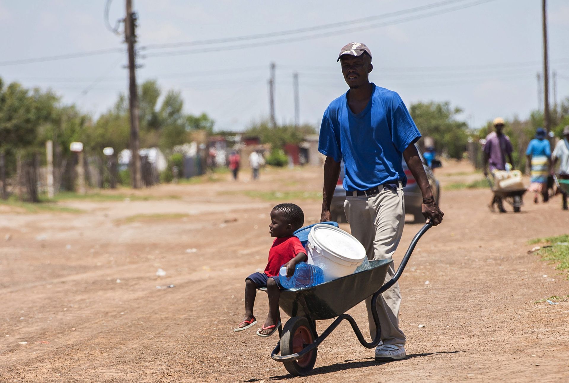 epa05152626 Residents push a wheelbarrow with water containers leaving a water distribution point in the rural farming town of Senekal, South Africa, 10 February 2016. The water is trucked to the town by local government sources. The town has had a severe water shortage for the past few months with residents having to queue for water at water hand out points. Large parts of this district and widespread areas of South Africa are experiencing the worst drought in 30 years as well as the highest temperatures in decades.  EPA/SHIRAAZ MOHAMED