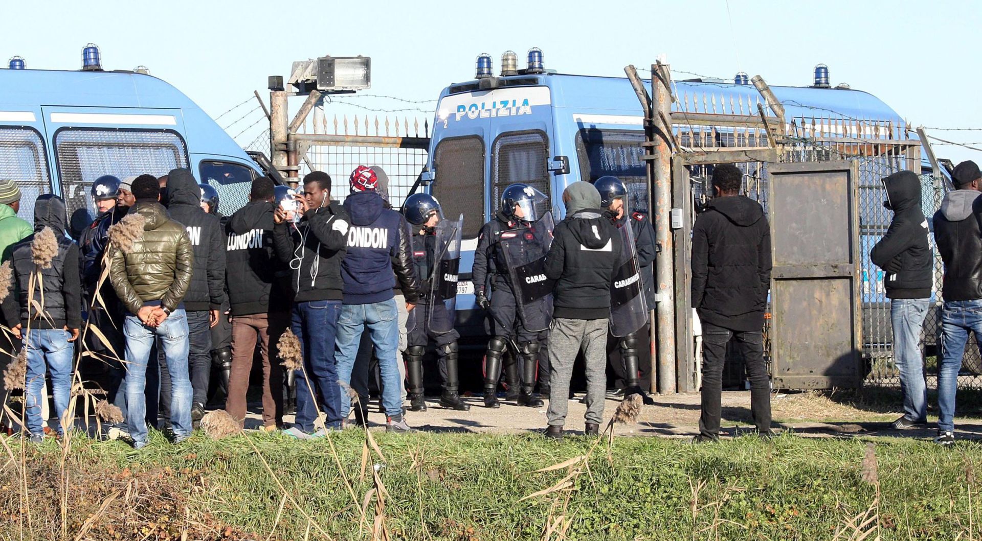 epa05696643 Police attend the scene of a protest near the Cona migrant center in Cona, Venice, Italy, 03 January 2017. Media reports that migrants were protesting the alleged delay in medical assistance to a young Ivorian woman who later died. The migrants set fires outside the center and no injuries were reported.  EPA/ANDREA MEROLA
