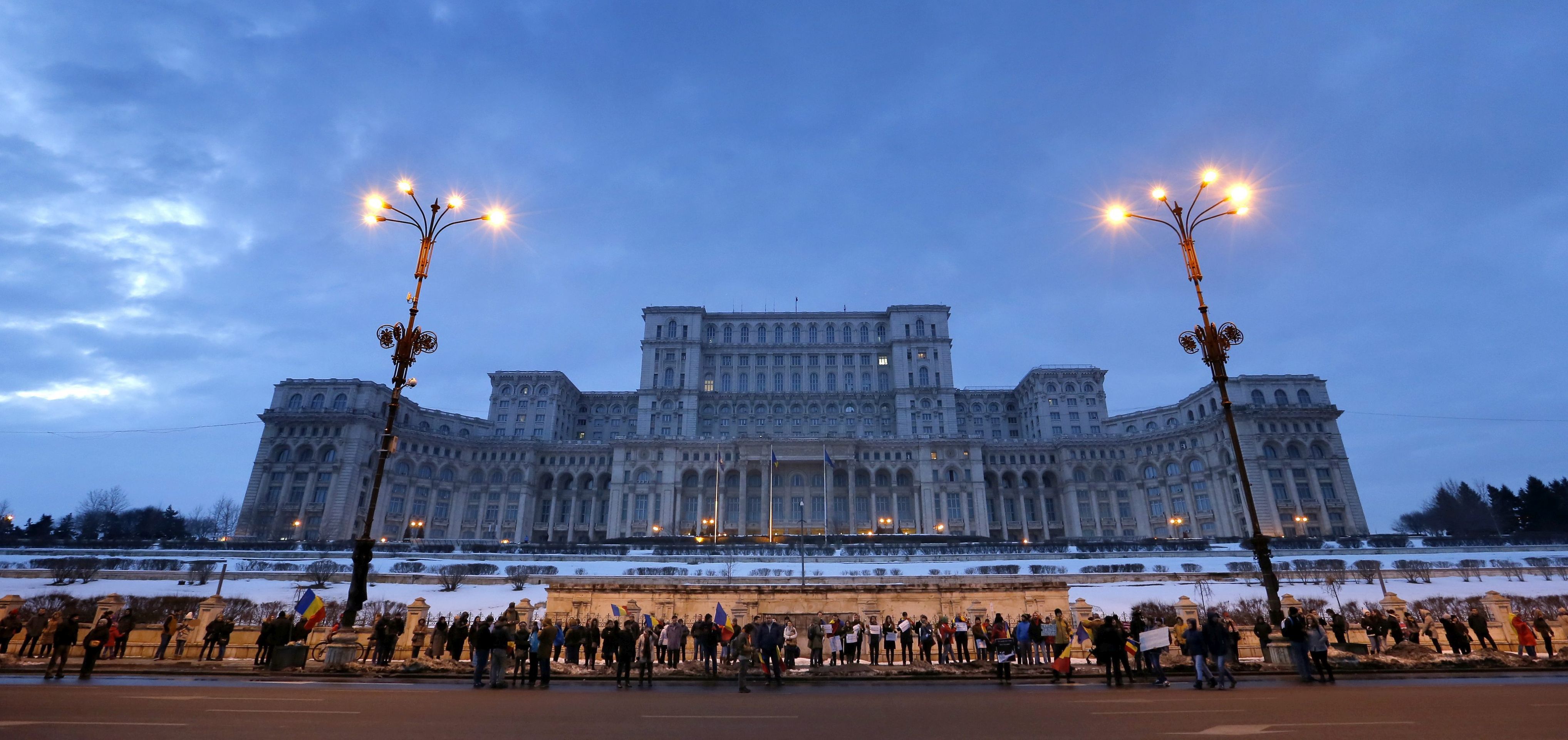 epa05771075 Romanian people with their children, wearing placards and shouting slogans, gather to form a human chain around the parliament building (background) after a protest march in Bucharest, Romania, 04 February 2017. About 15,000 people gathered in front of government building and blocked the city traffic with a protest march against a government bill  that was passed during a government session on late 31 January, as a government ordinance to pardon those sentenced to jail terms shorter than five years.  EPA/ROBERT GHEMENT