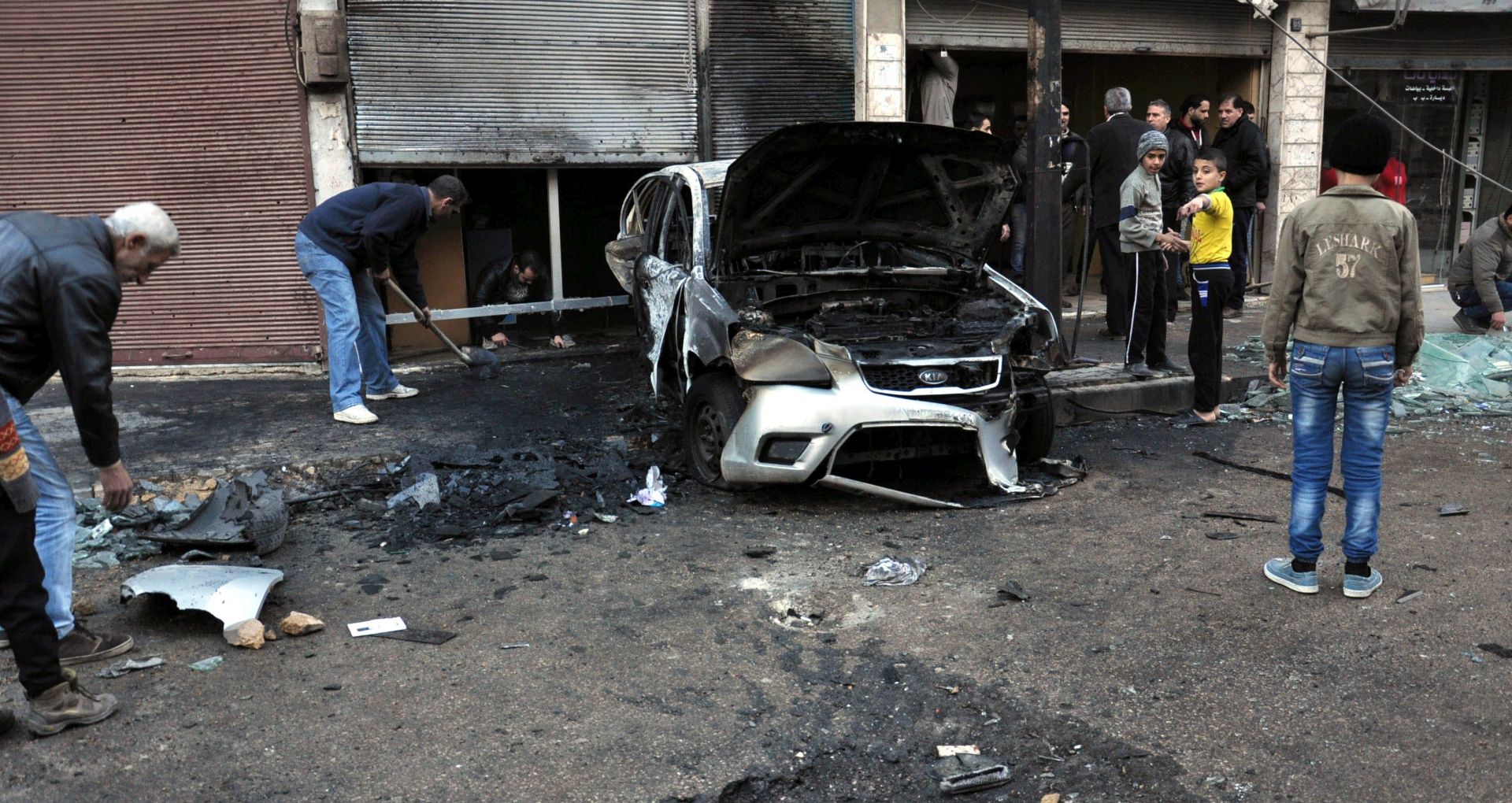 epa05783622 A handout photo made available by the official Syrian Arab News Agency (SANA) shows people standing near a burnt-out car at the site of what SANA claim to be rocket attacks, in Homs, Syria, 10 February 2017.  According to SANA, rocket attacks on the residential neighborhoods of Homs city killed one person and injured 12 others. The Syrian Observatory for Human Rights said five people were killed in regime bombings in the besieged al-Waer neighborhood in the Syrian city of Homs.  EPA/SANA HANDOUT  HANDOUT EDITORIAL USE ONLY/NO SALES