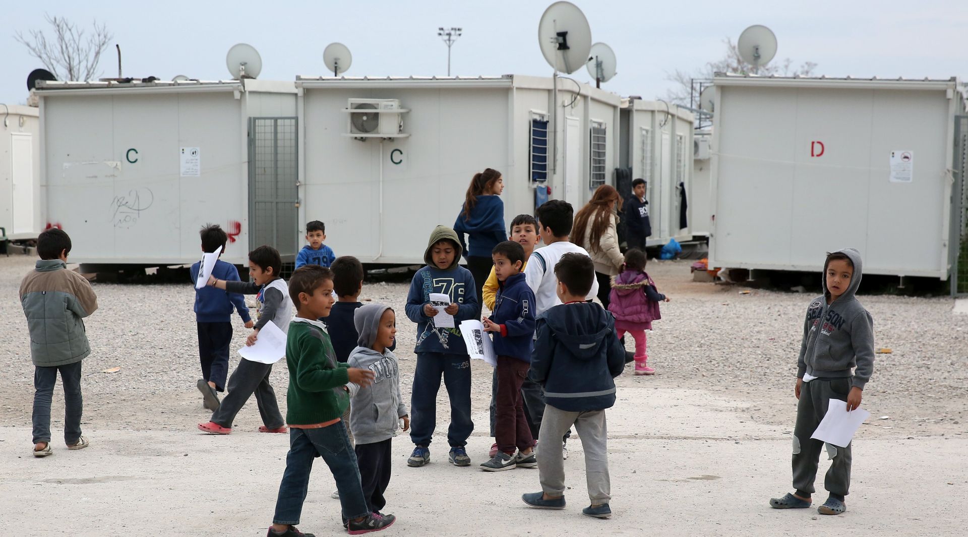 epa05804357 Children stand at the entrance of a refugee camp in Eleonas, as they attend a protest demanding better living conditions, in Athens, Greece, 19 February 2017. Some Greek nationals join with refugees and migrants to protest against squalid living conditions at the camp of Eleonas.  EPA/SIMELA PANTZARTZI